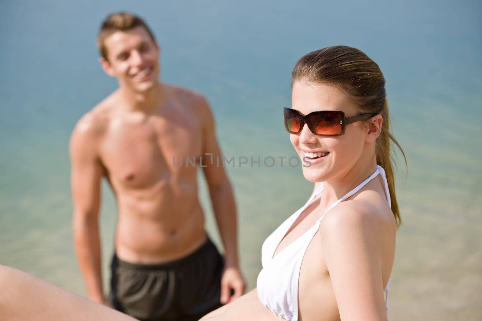 Young couple sunbathing by sea on beach
