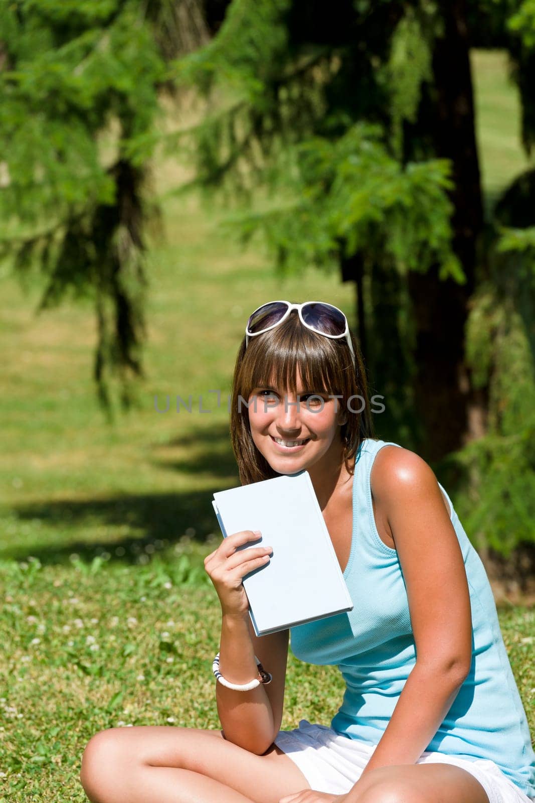 Smiling young woman read book in park