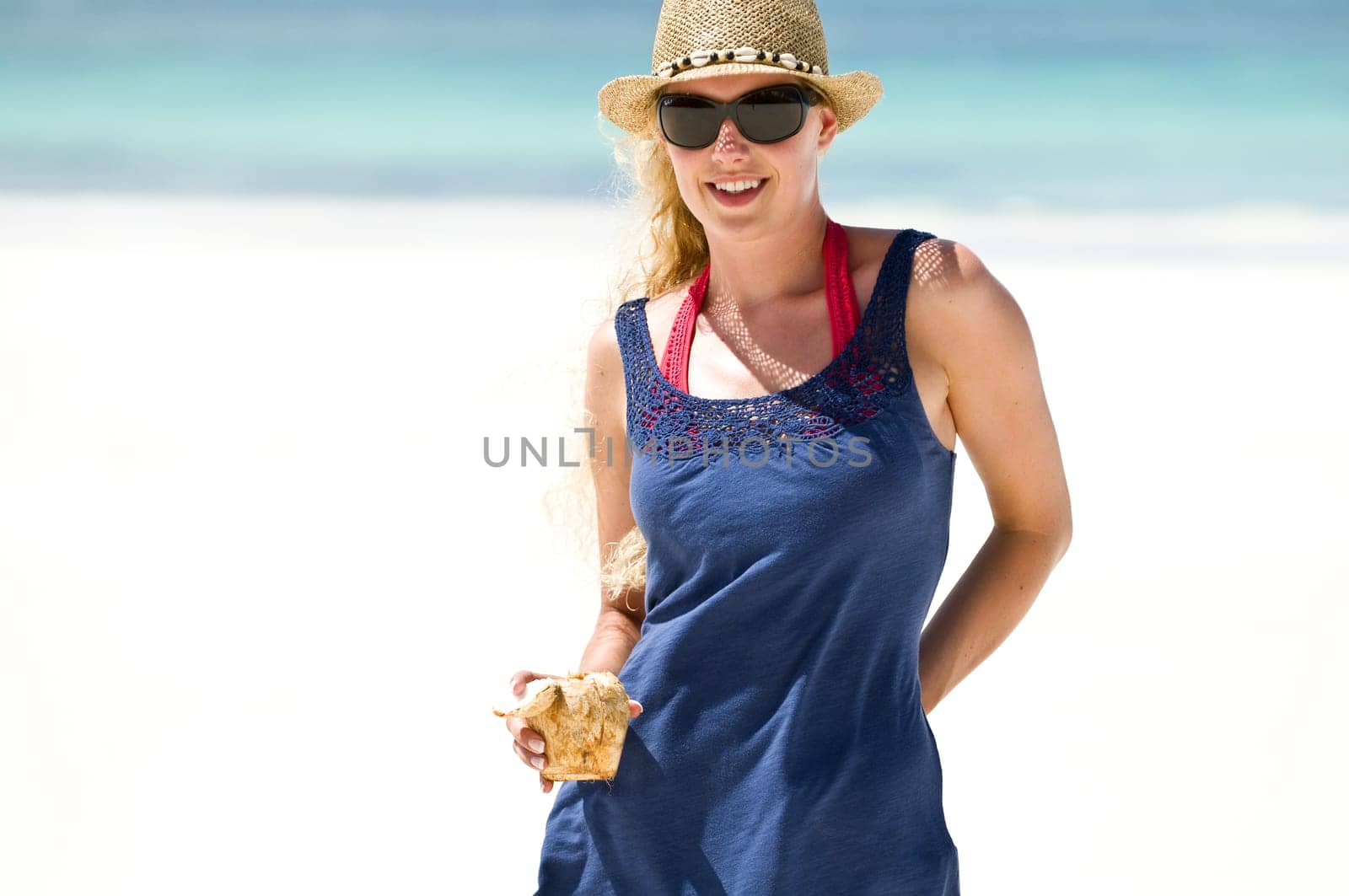 Young woman having coconut drink on the beach