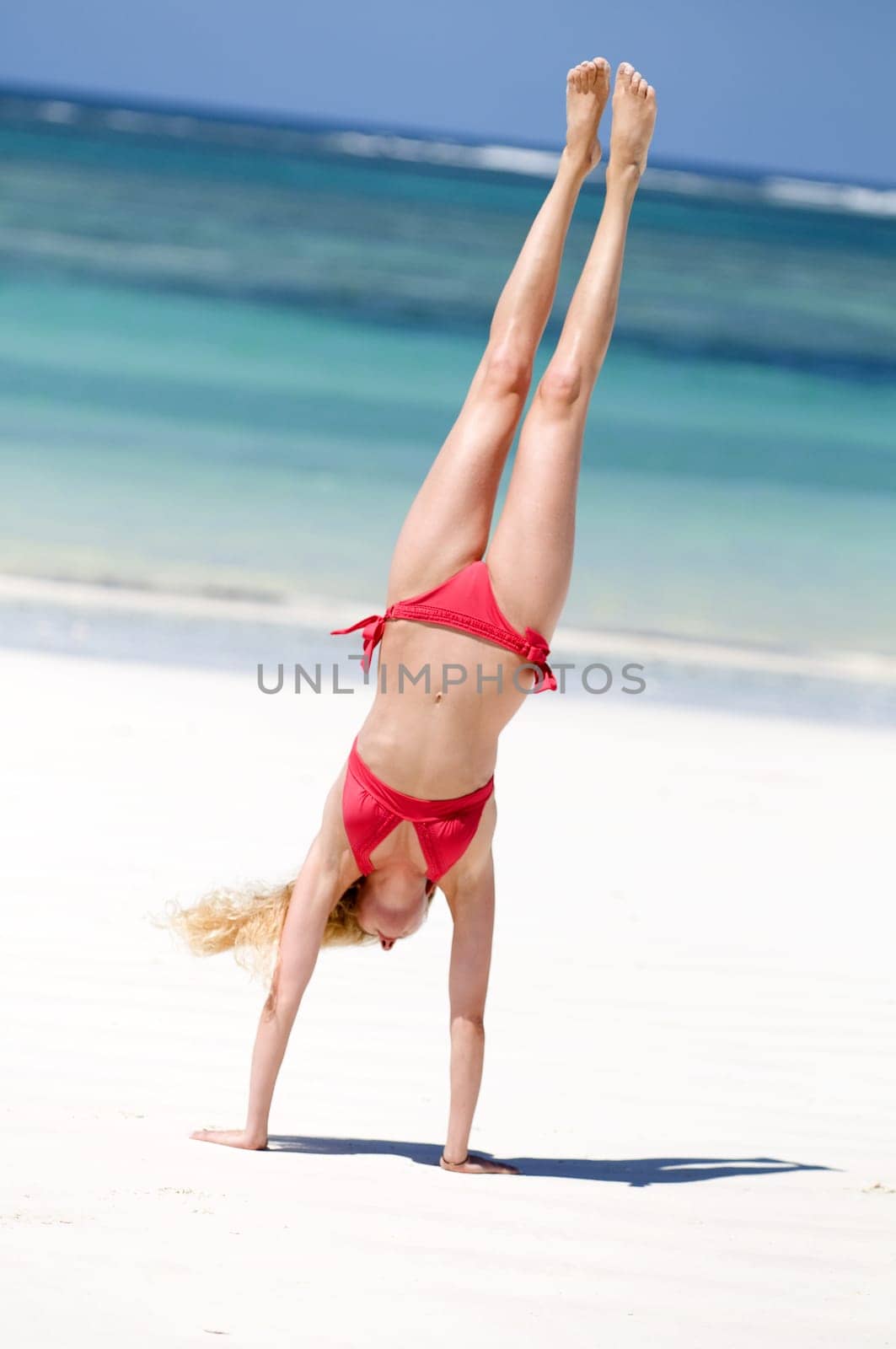 Woman doing handstand on the beach