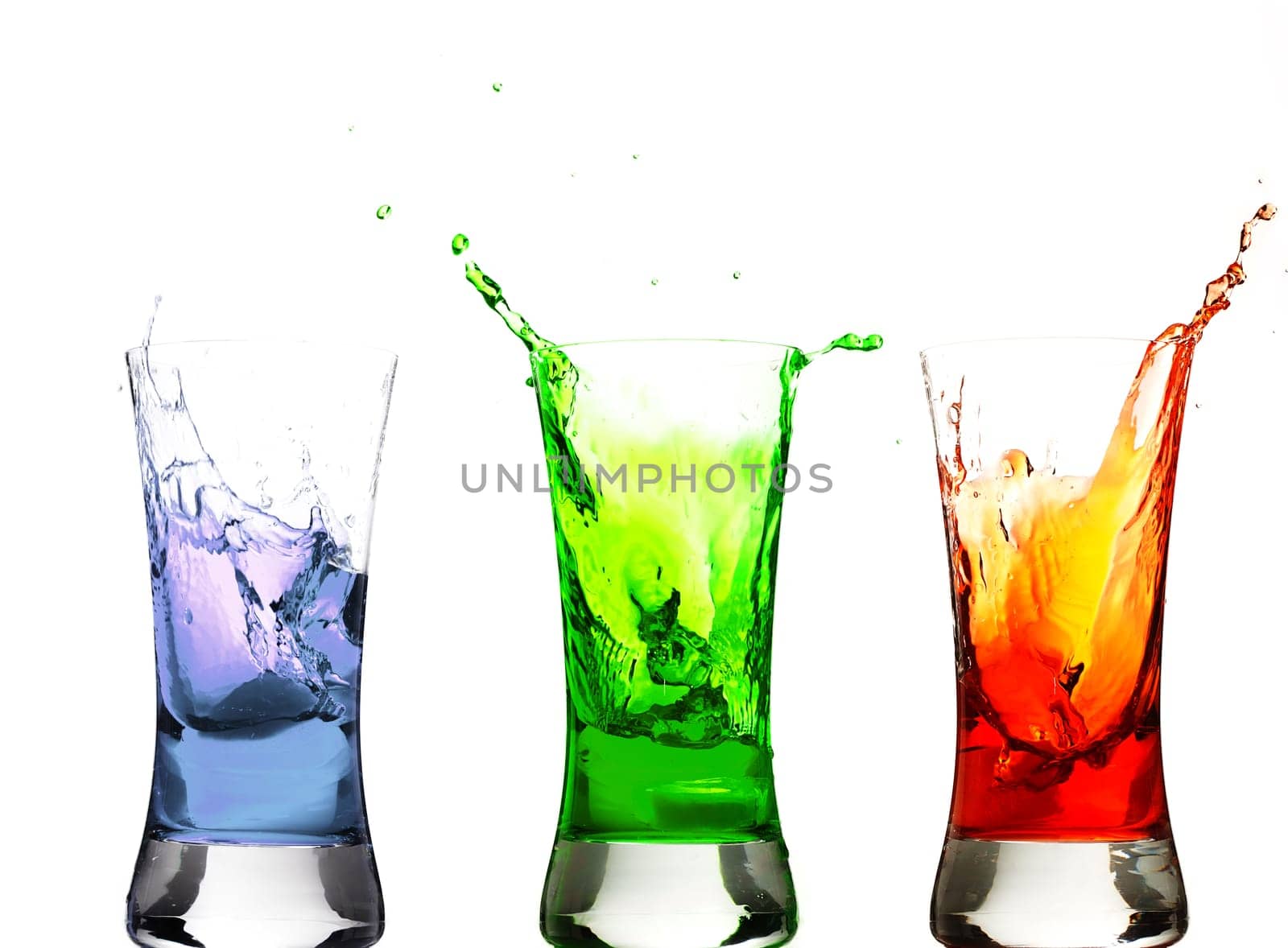 Ice cubes falling into colorful glasses
