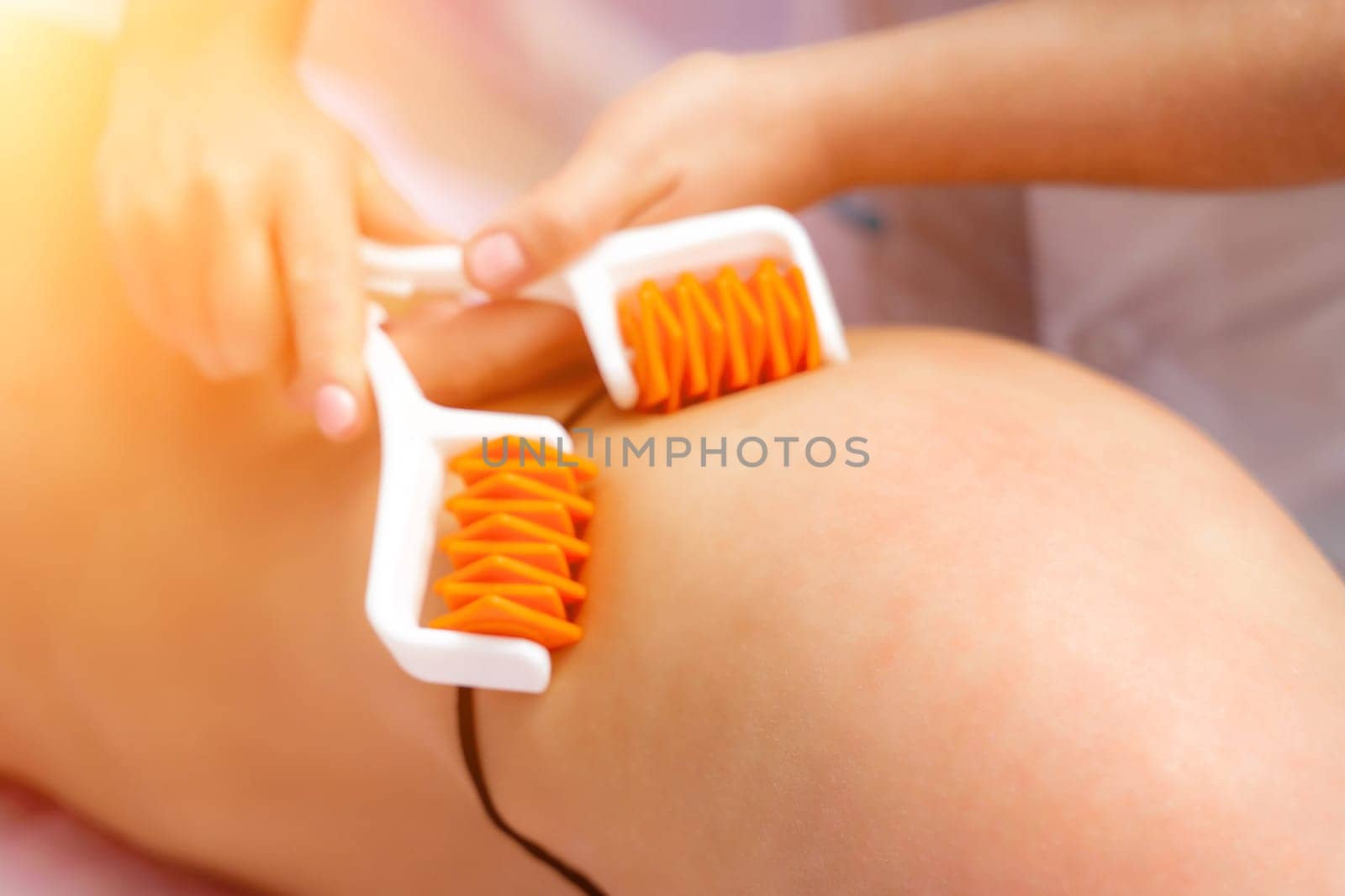 The masseur makes anti-cellulite massage using a roller massager. Physiotherapy and rehabilitation treatment