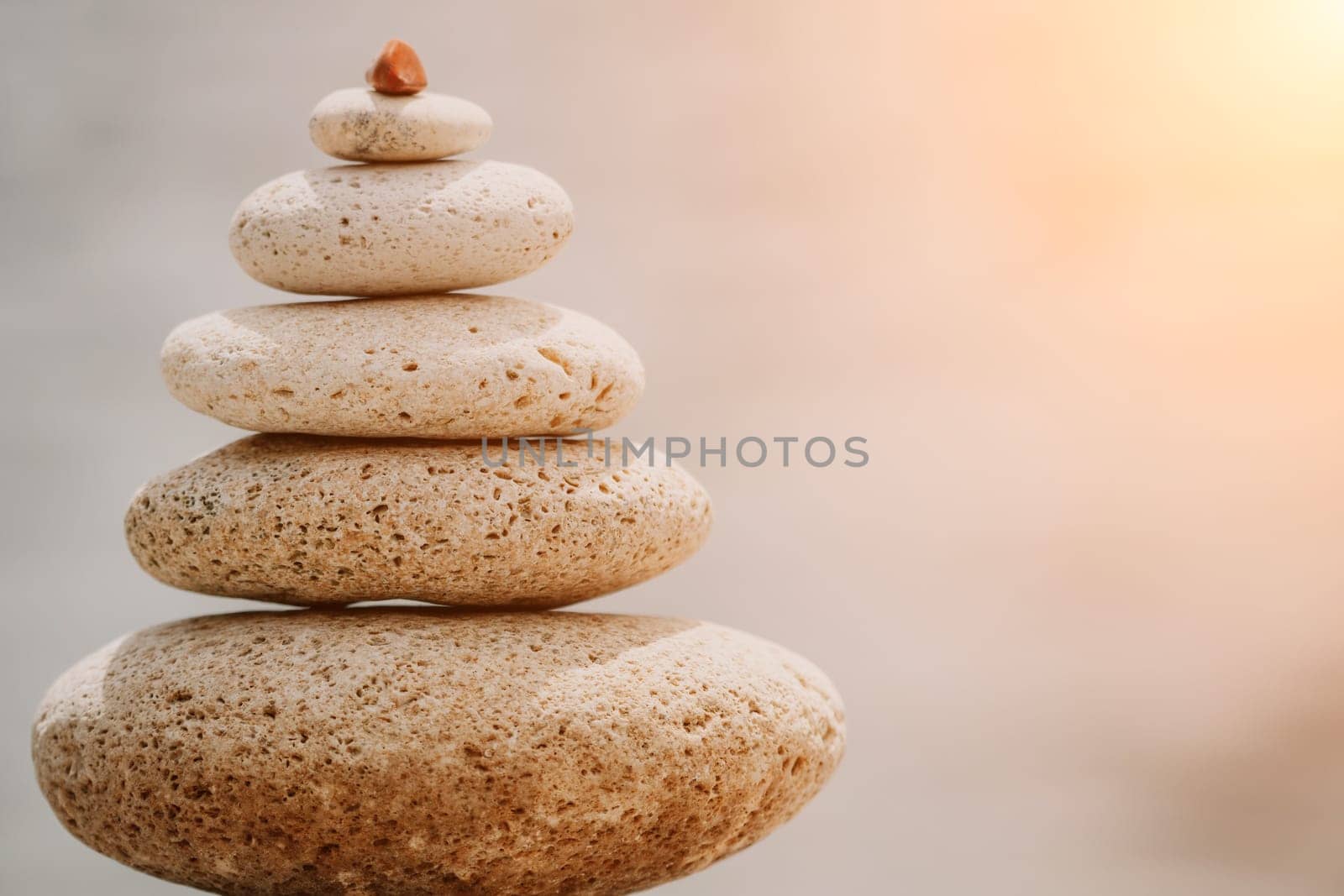 Pyramid stones on seashore with warm sunset on sea background for perfect holiday. Pebble beach and calm sea create a serene travel destination. concepts of happy vacation, meditation spa and calmness by panophotograph