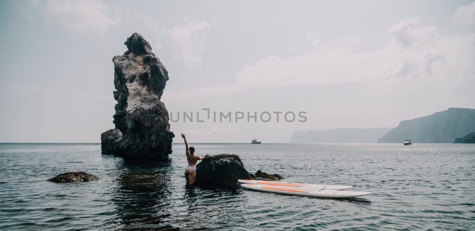 Woman sup yoga. Middle age sporty woman practising yoga pilates on paddle sup surfboard. Female stretching doing workout on sea water. Modern individual hipster outdoor summer sport activity