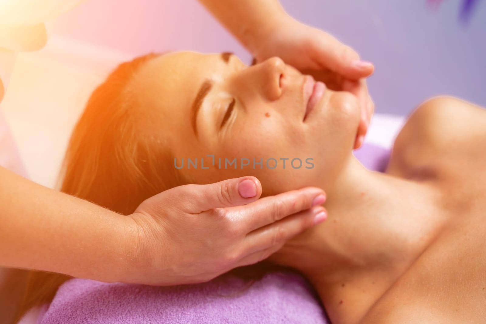 Relaxing massage. European woman getting facial massage in spa salon, side view.