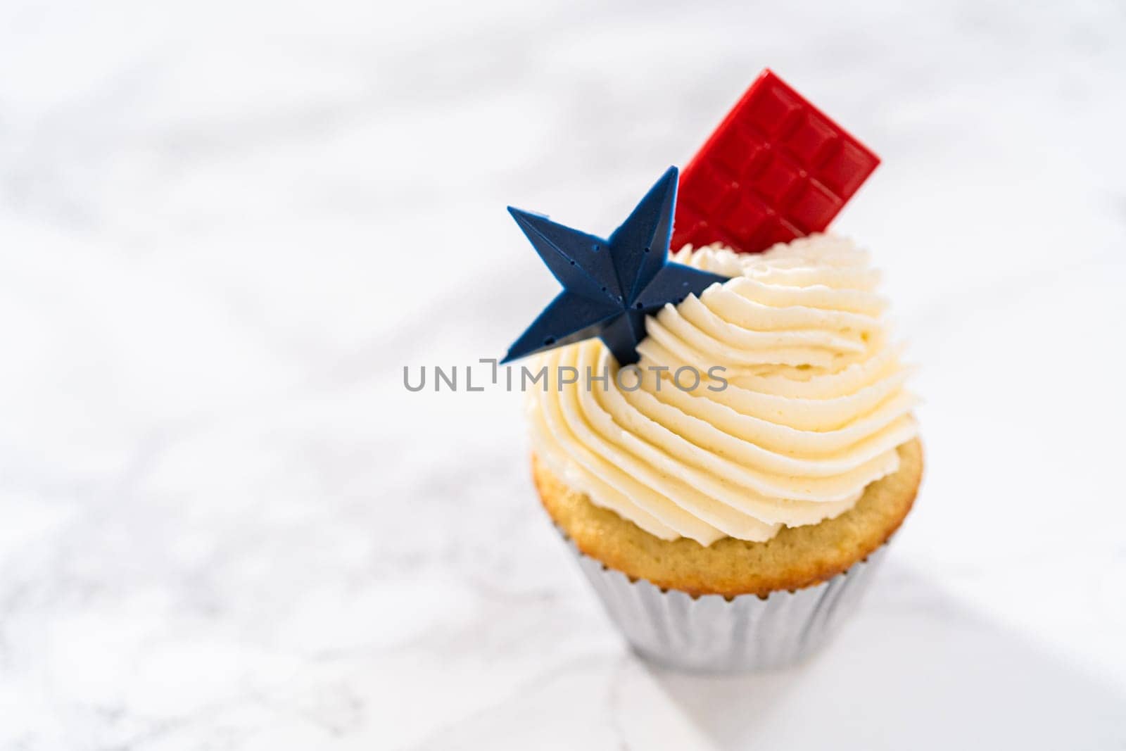 Lemon cupcakes with lemon buttercream frosting, and decorated with patriotic blue chocolate star and red mini chocolate.