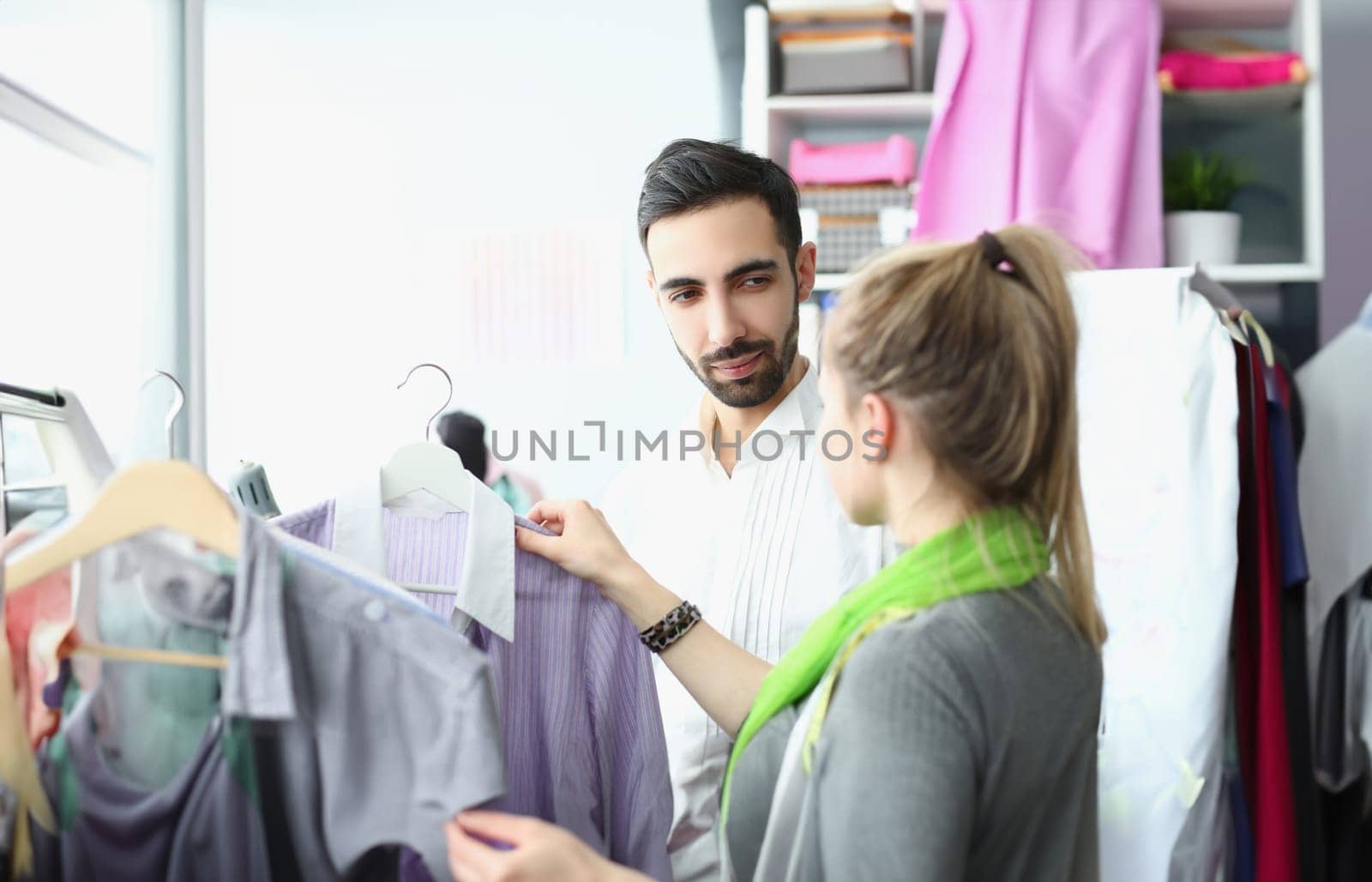 Portrait of female and male coworkers share ideas about new fashion collection. Talented dressmaker help costumer with choice. Store, mall, atelier concept