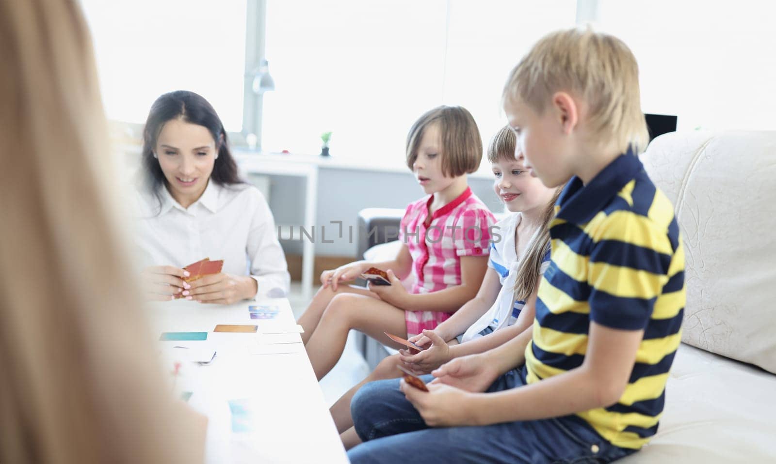 Portrait of children hold playing cards, game with parents at home, games for development. Education, weekend, parenthood, childhood, indoor fun concept