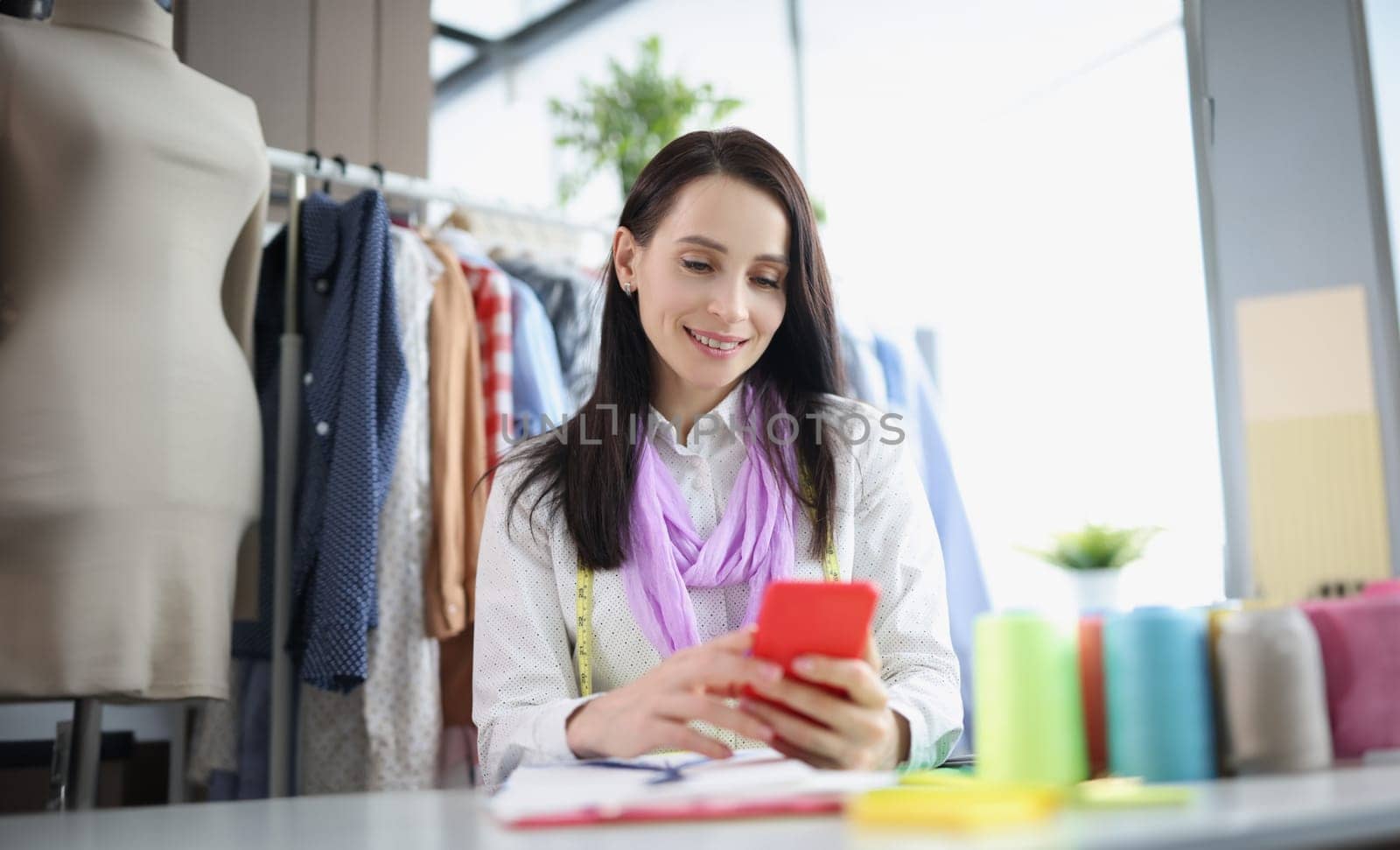 Portrait of brunette woman take order online, sell clothes over internet, promote website. Fashionable atelier with high quality garment. Business concept