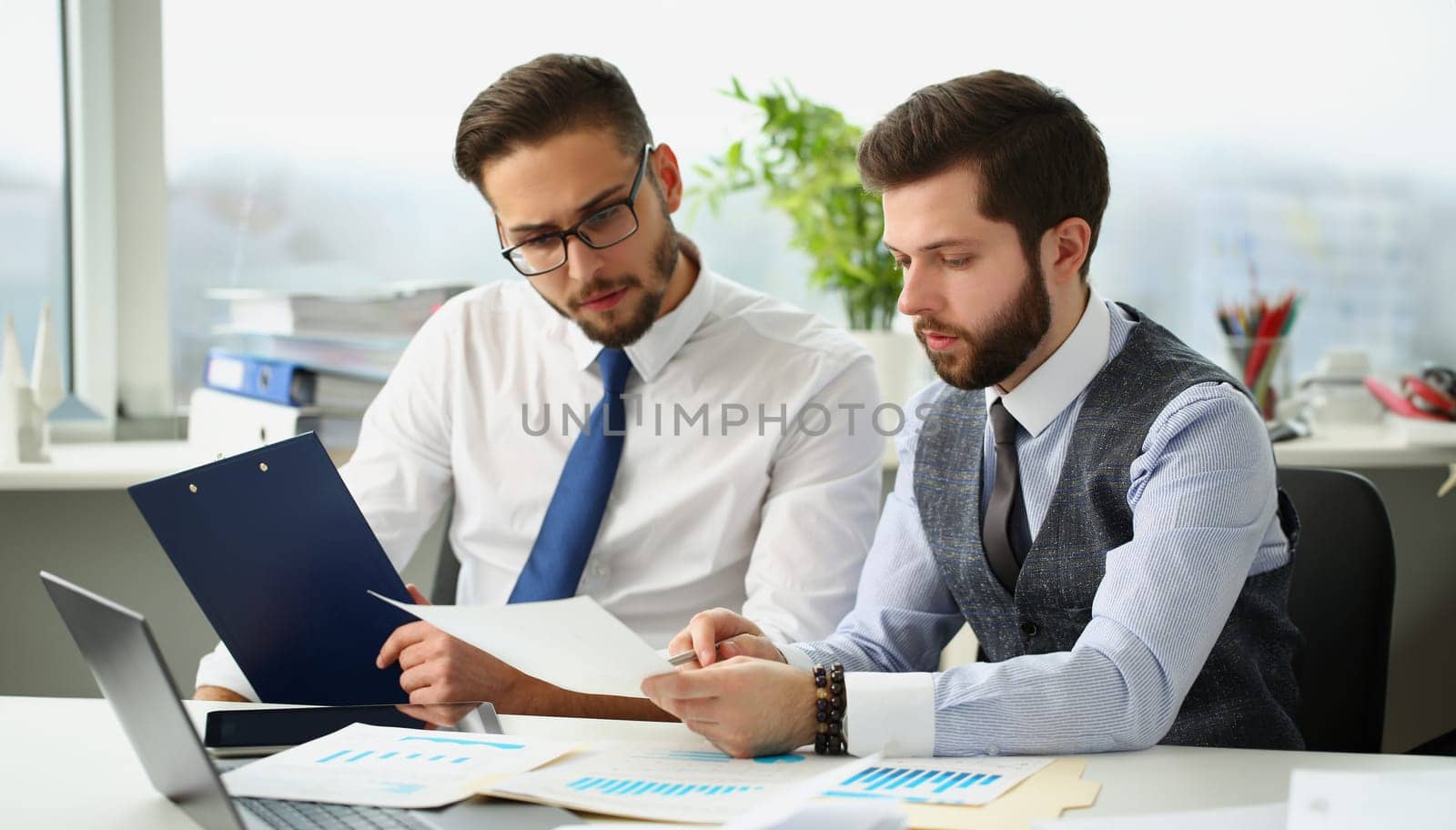 Portrait of coworkers men go through financial papers, solve and discuss problems. Fresh look on situation, new angle, white collar. Investment concept