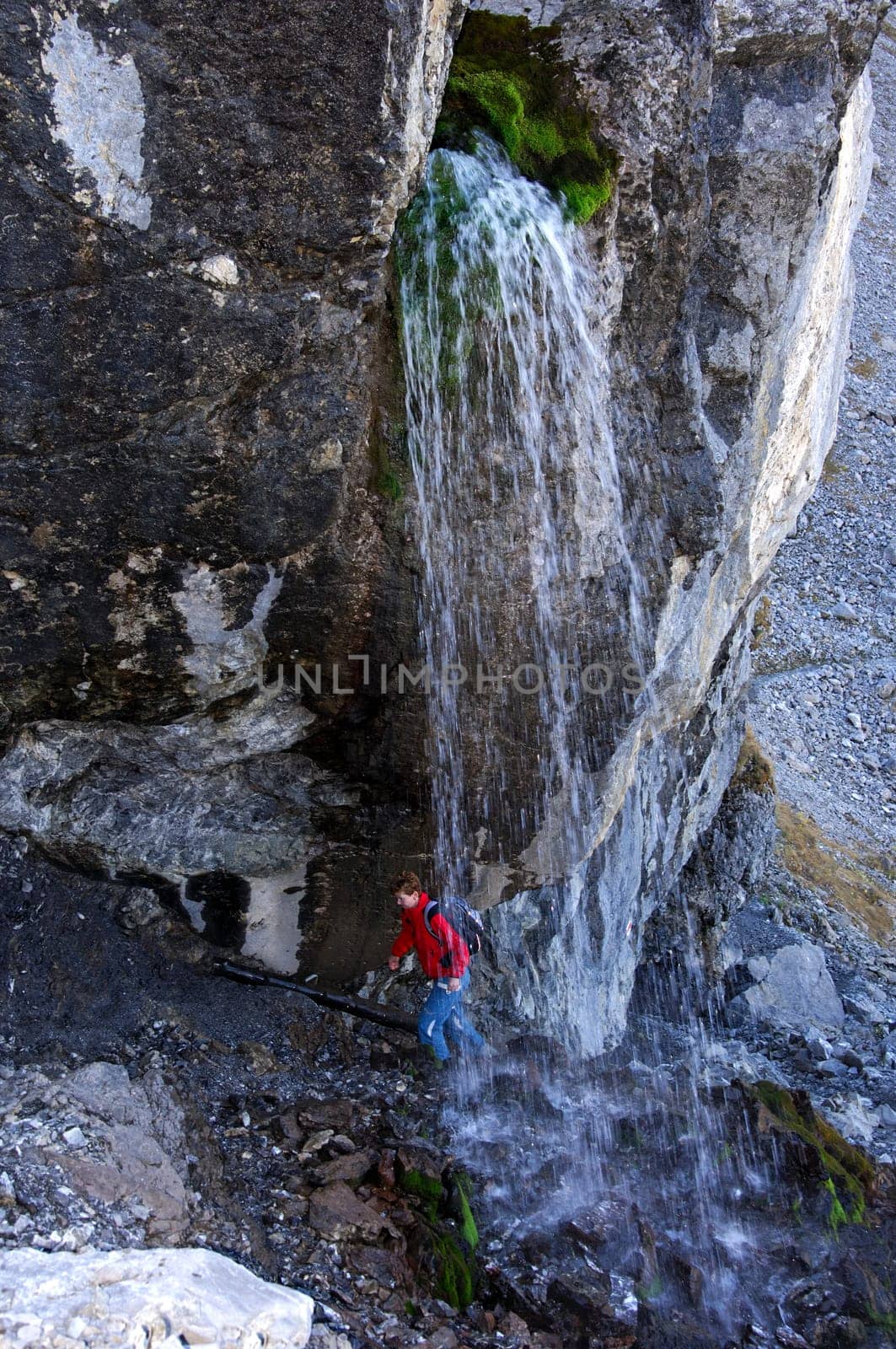 Hiker crosses a refreshing waterfall,Alps