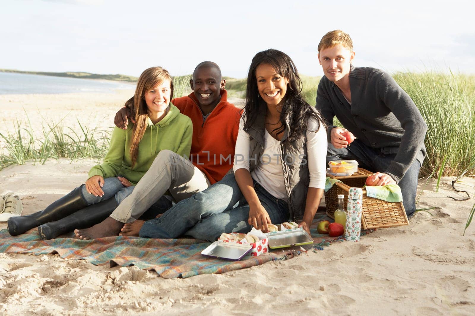 Group Of Young Friends Enjoying Picnic On Beach Together