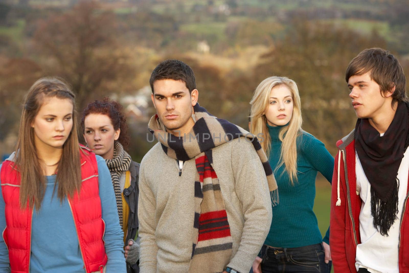 Teenage Boy Surrounded By Friends In Outdoor Autumn Landscape