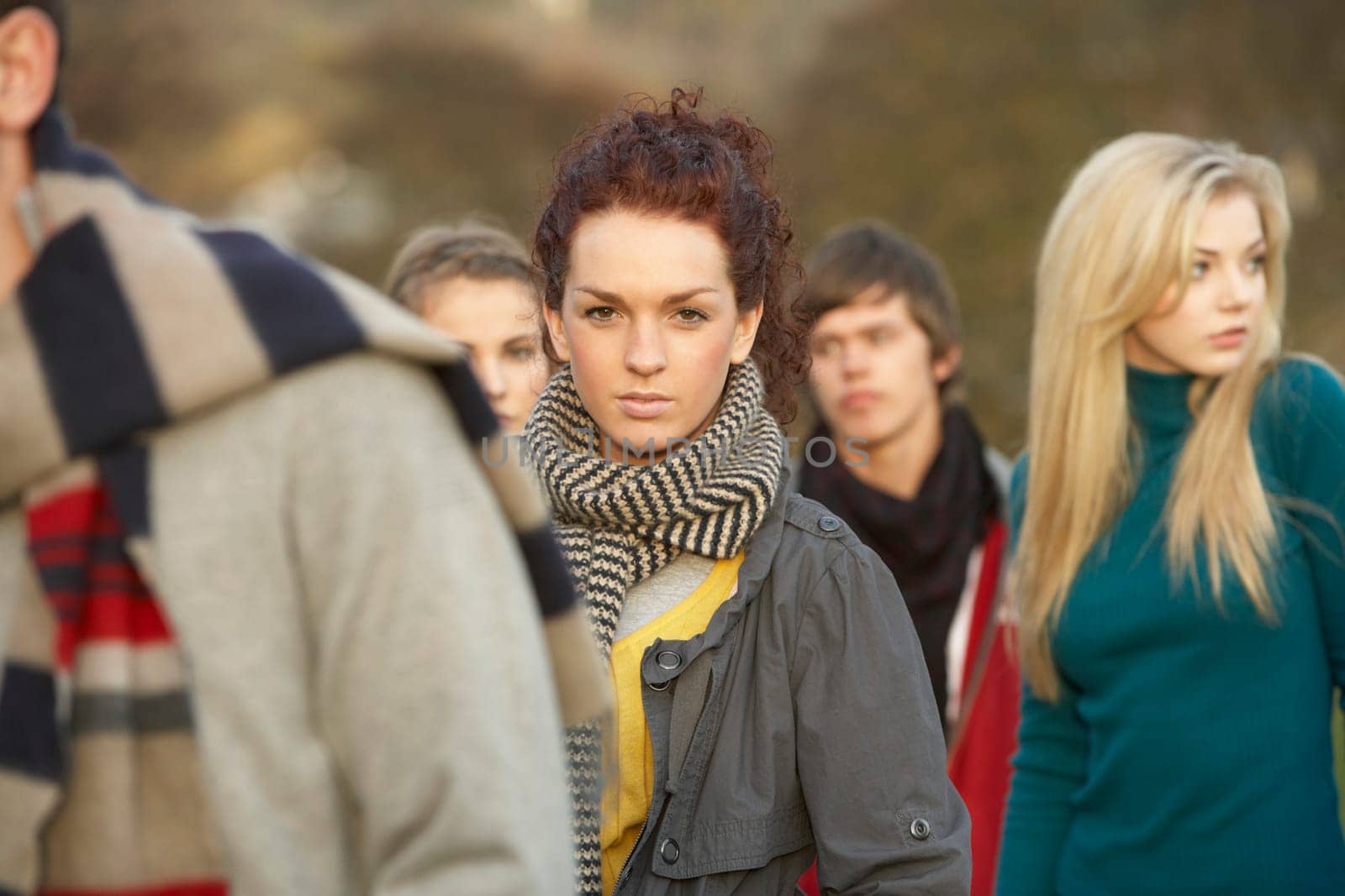 Teenage Girl Surrounded By Friends In Outdoor Autumn Landscape