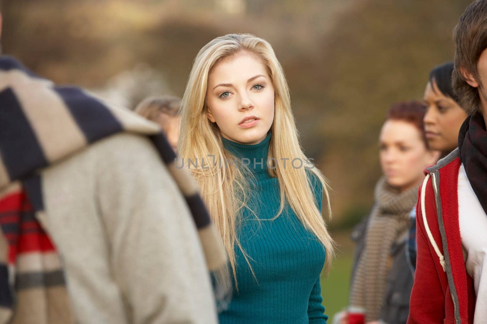 Teenage Girl Surrounded By Friends In Outdoor Autumn Landscape