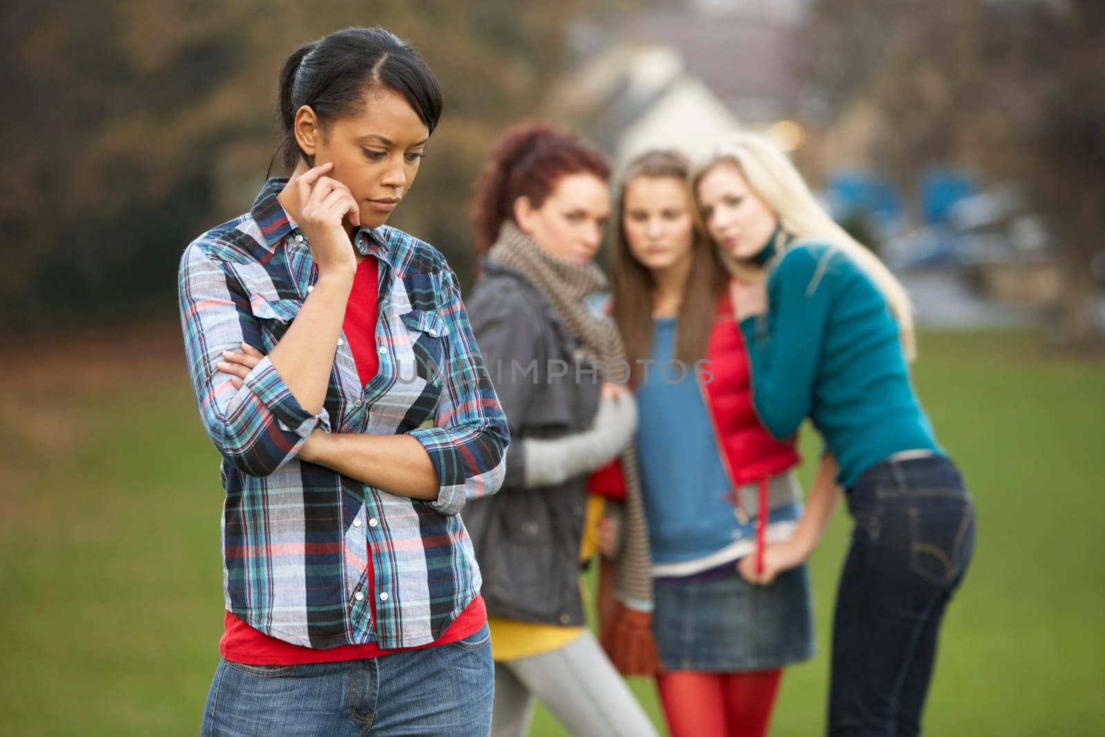 Upset Teenage Girl With Friends Gossiping In Background