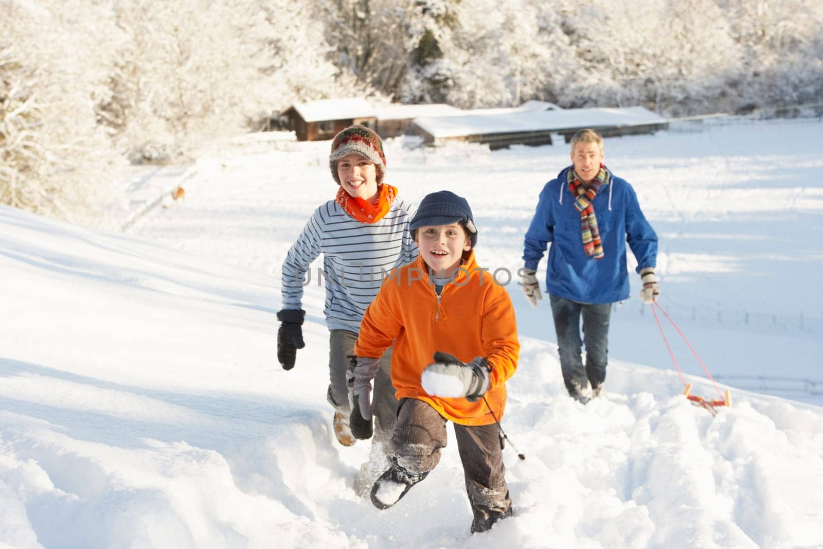 Father And Children Pulling Sledge Up Snowy Hill