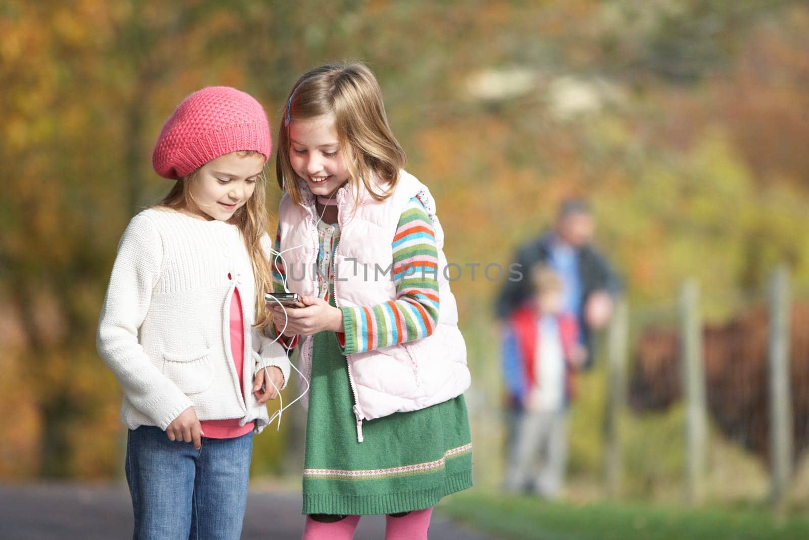 Two Young Girl Listening To MP3 Player Outdoors