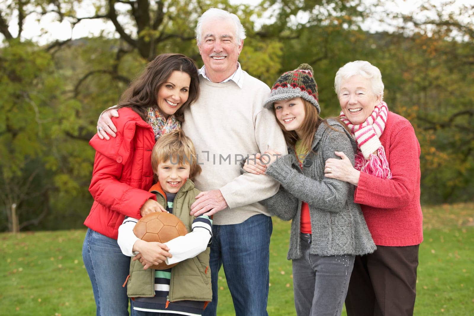 Grandparents With Grandchildren And Mother Holding Football Outside