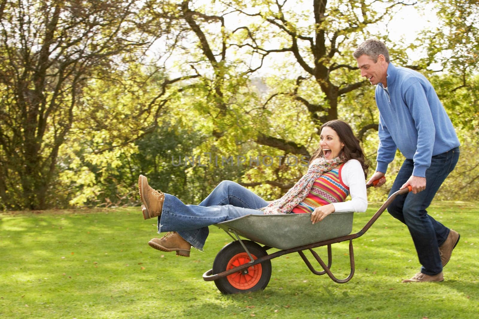 Couple With Man Giving Woman Ride In Wheelbarrow