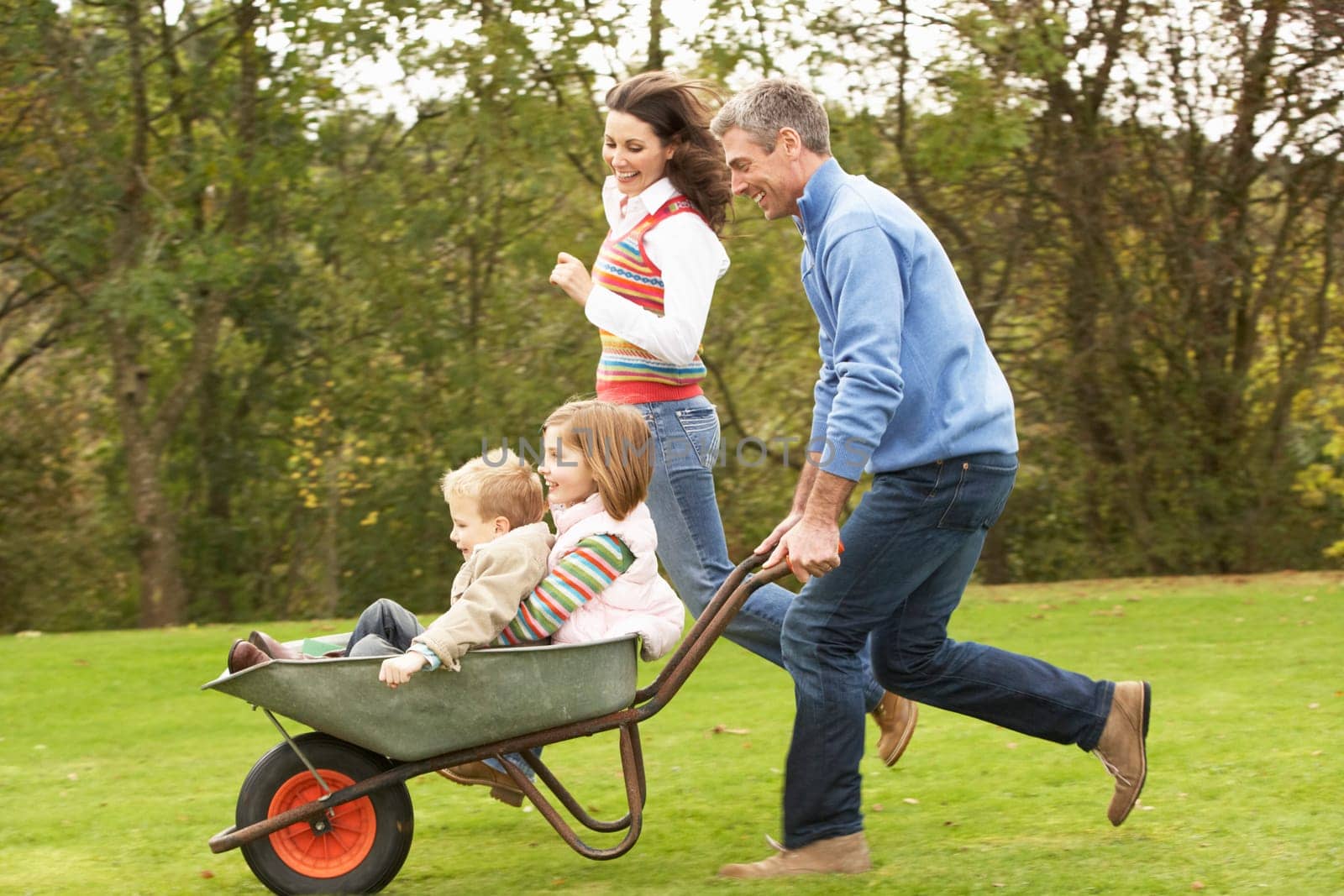Parents Giving Children Ride In Wheelbarrow
