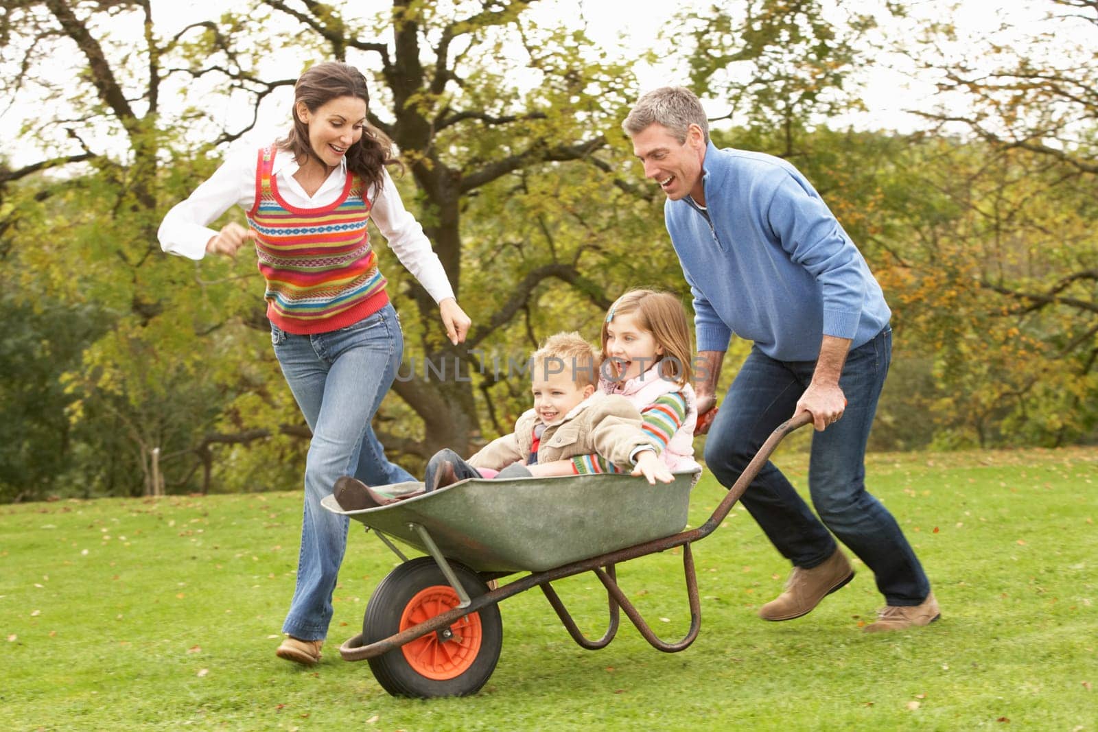 Parents Giving Children Ride In Wheelbarrow