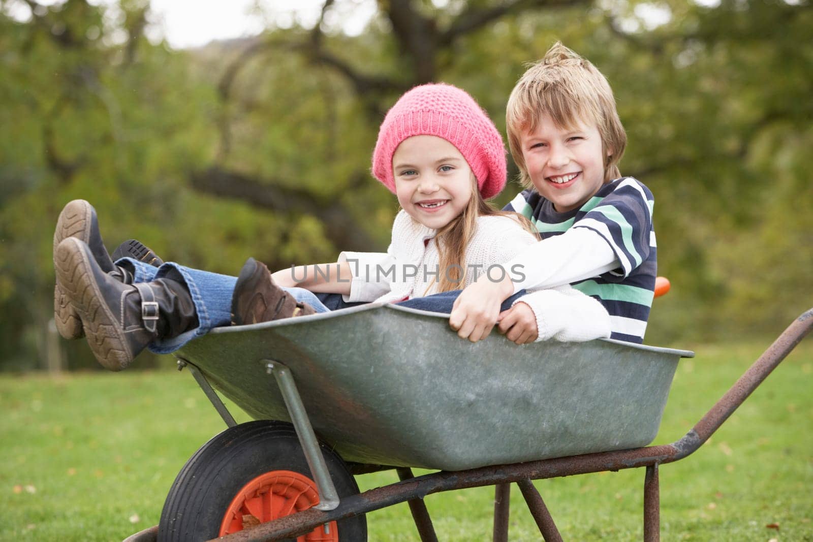 Boy And Girl Sitting In Wheelbarrow