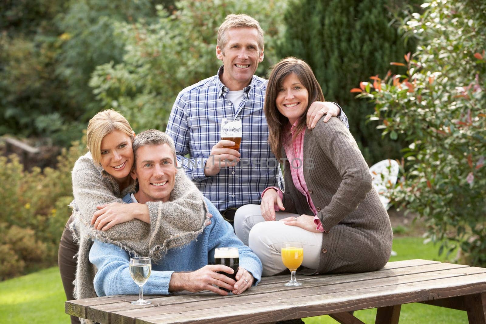 Group Of Friends Outdoors Enjoying Drink In Pub Garden