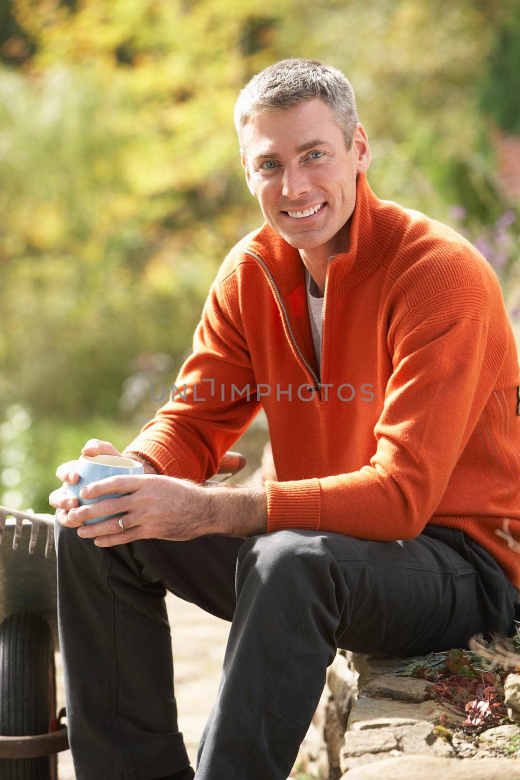 Man Having Coffee Break Whilst Working Outdoors In Garden