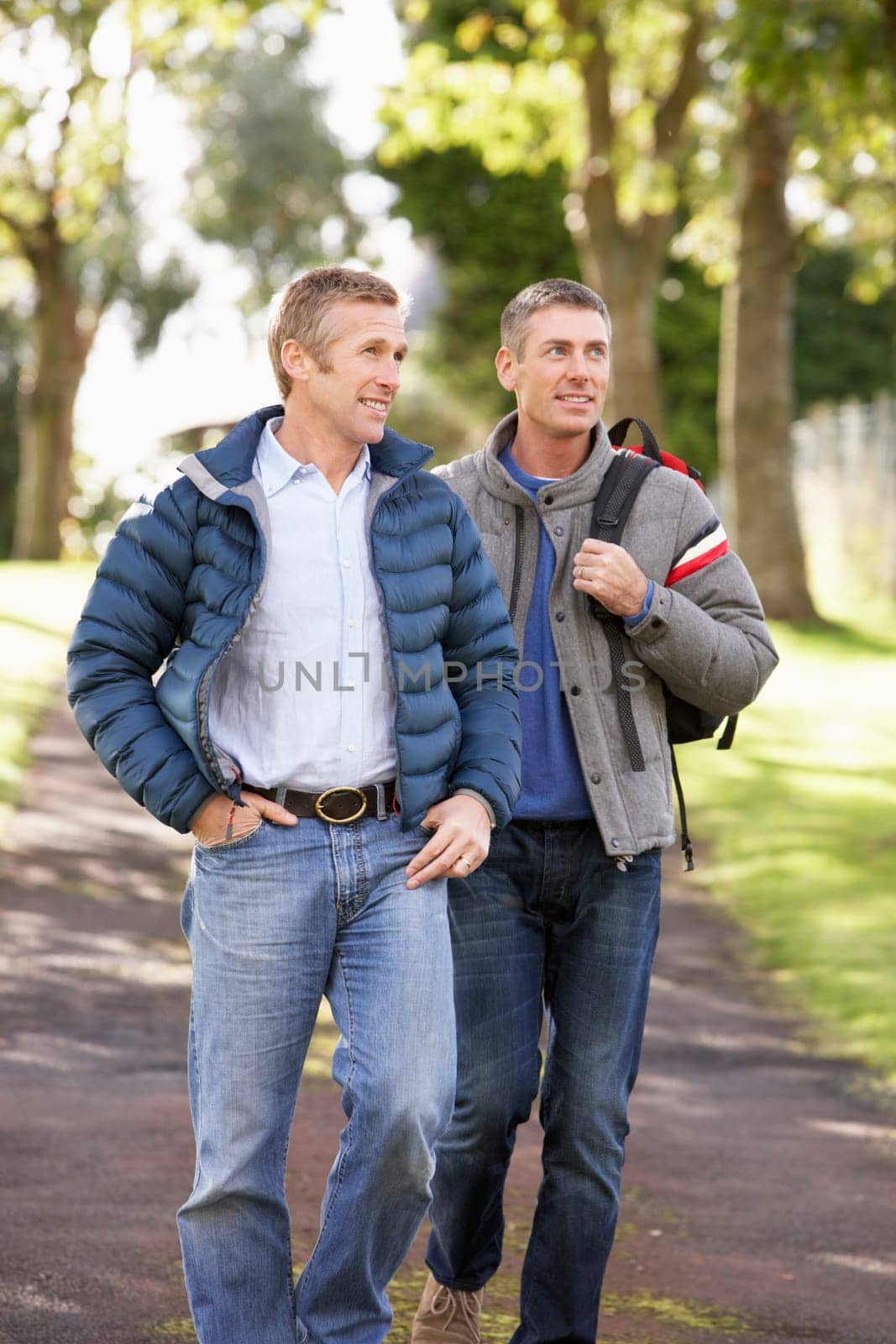 Two Male Friends Walking Outdoors In Autumn Park Together