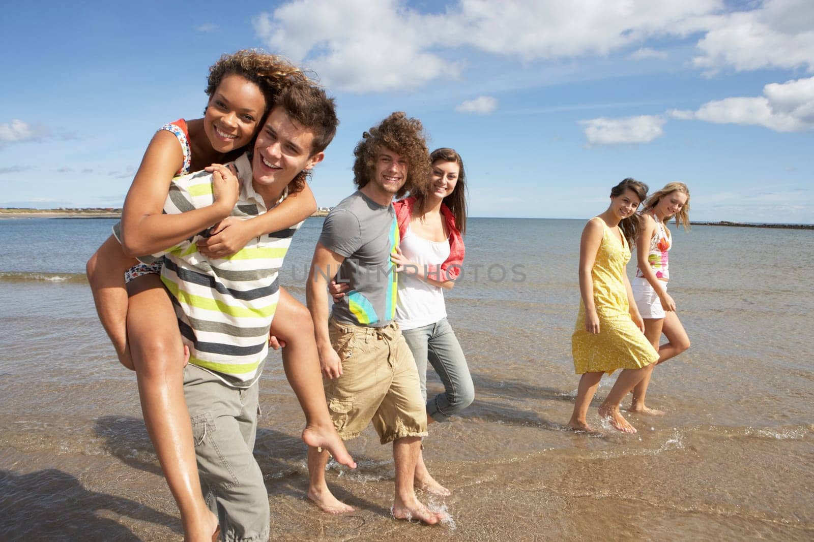 Group Of Young Friends Walking Along Summer Shoreline