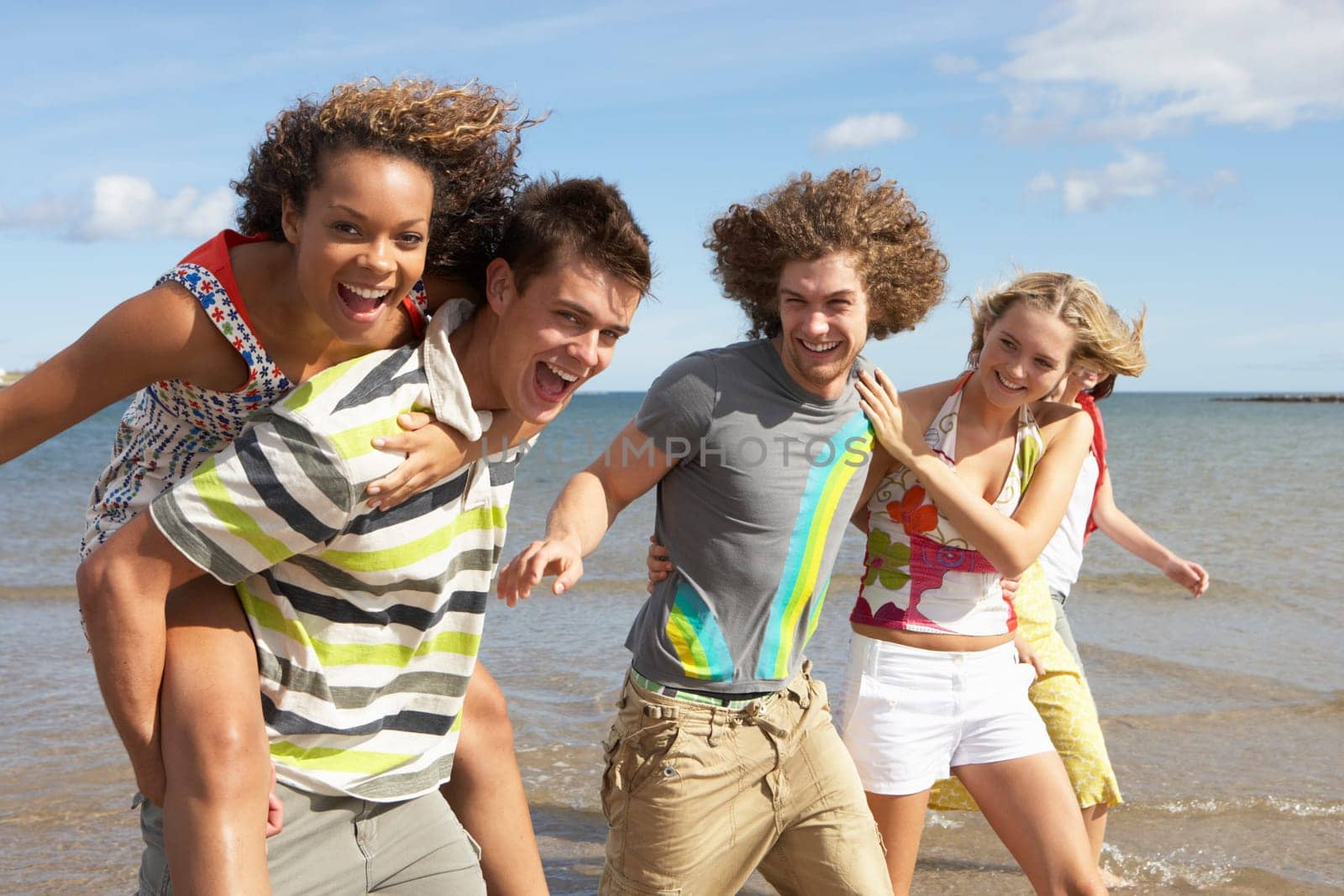 Group Of Young Friends Walking Along Summer Shoreline