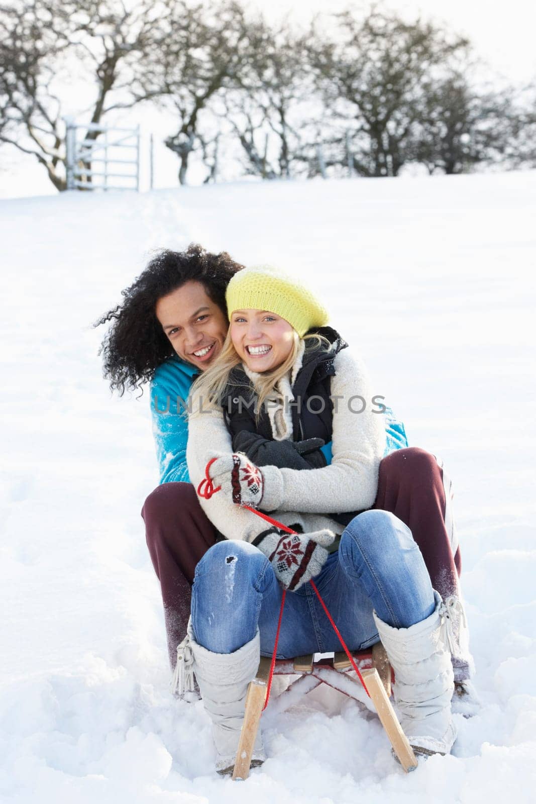 Couple Sledging Through Snowy Woodland