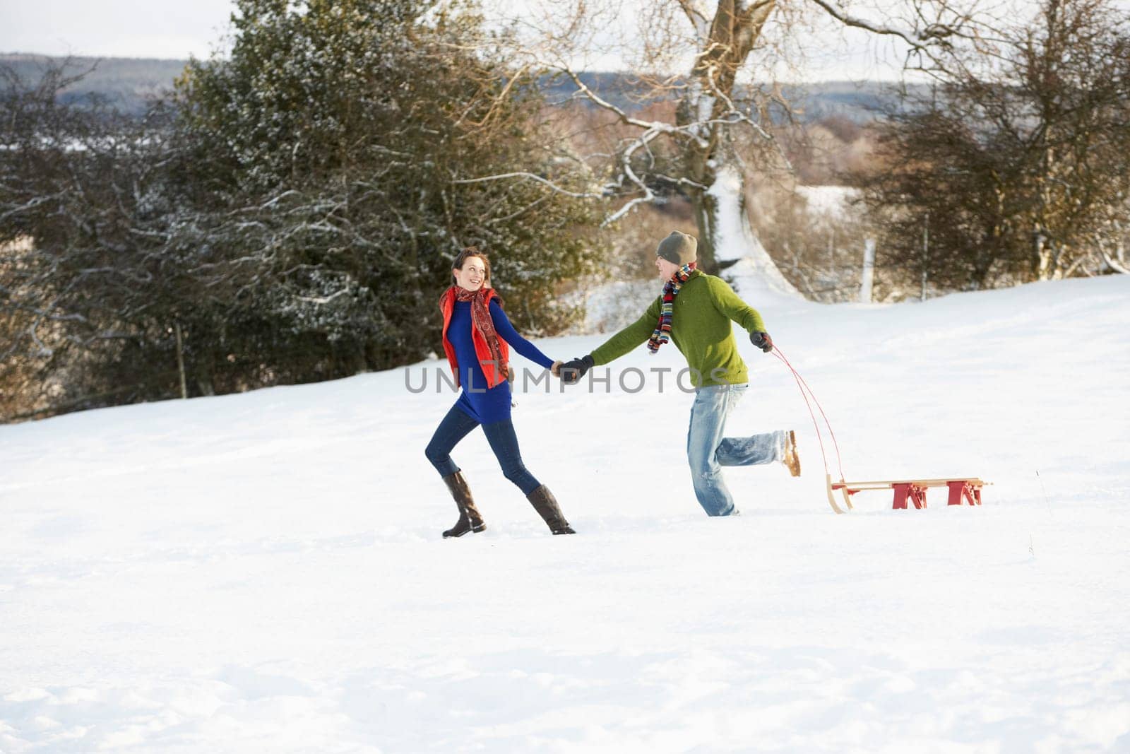 Teenage Couple Pulling Sledge Across Snowy Field