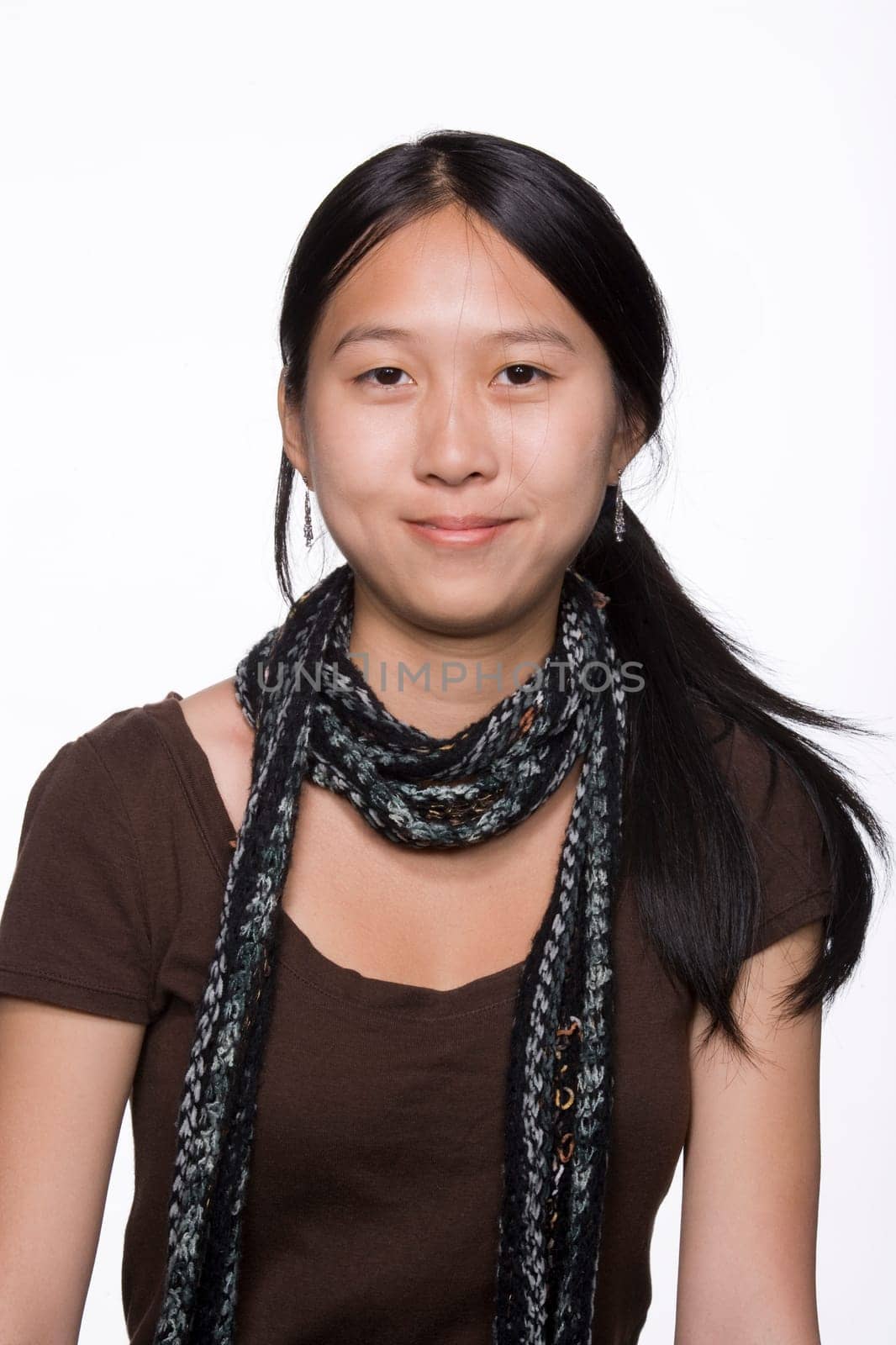 A portrait of a young adult woman smiling at the camera. She is dressed casually and wearing a scarf. Vertical shot. Isolated on white.