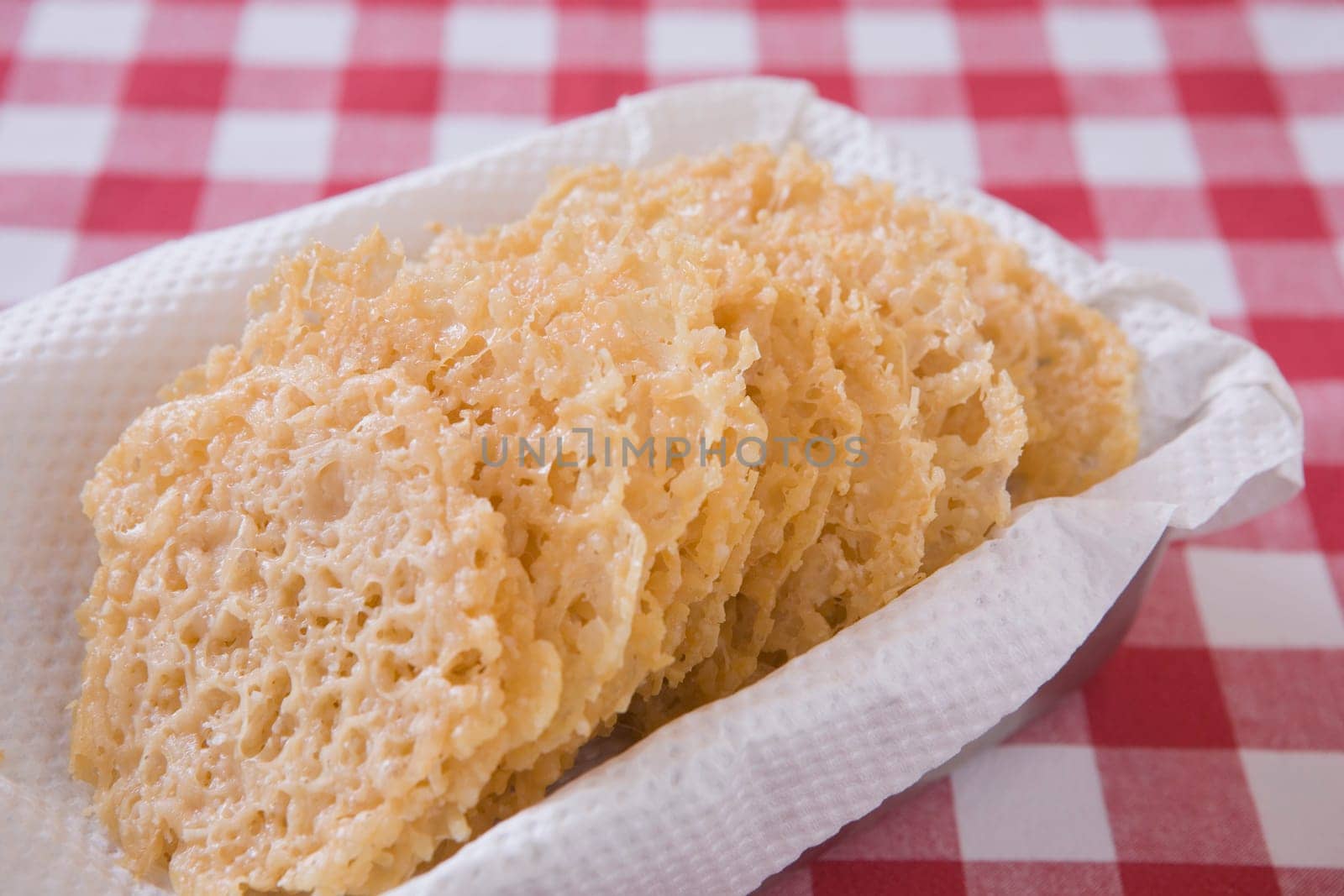 parmesan cheese laces in a basket on a red checkered table cloth