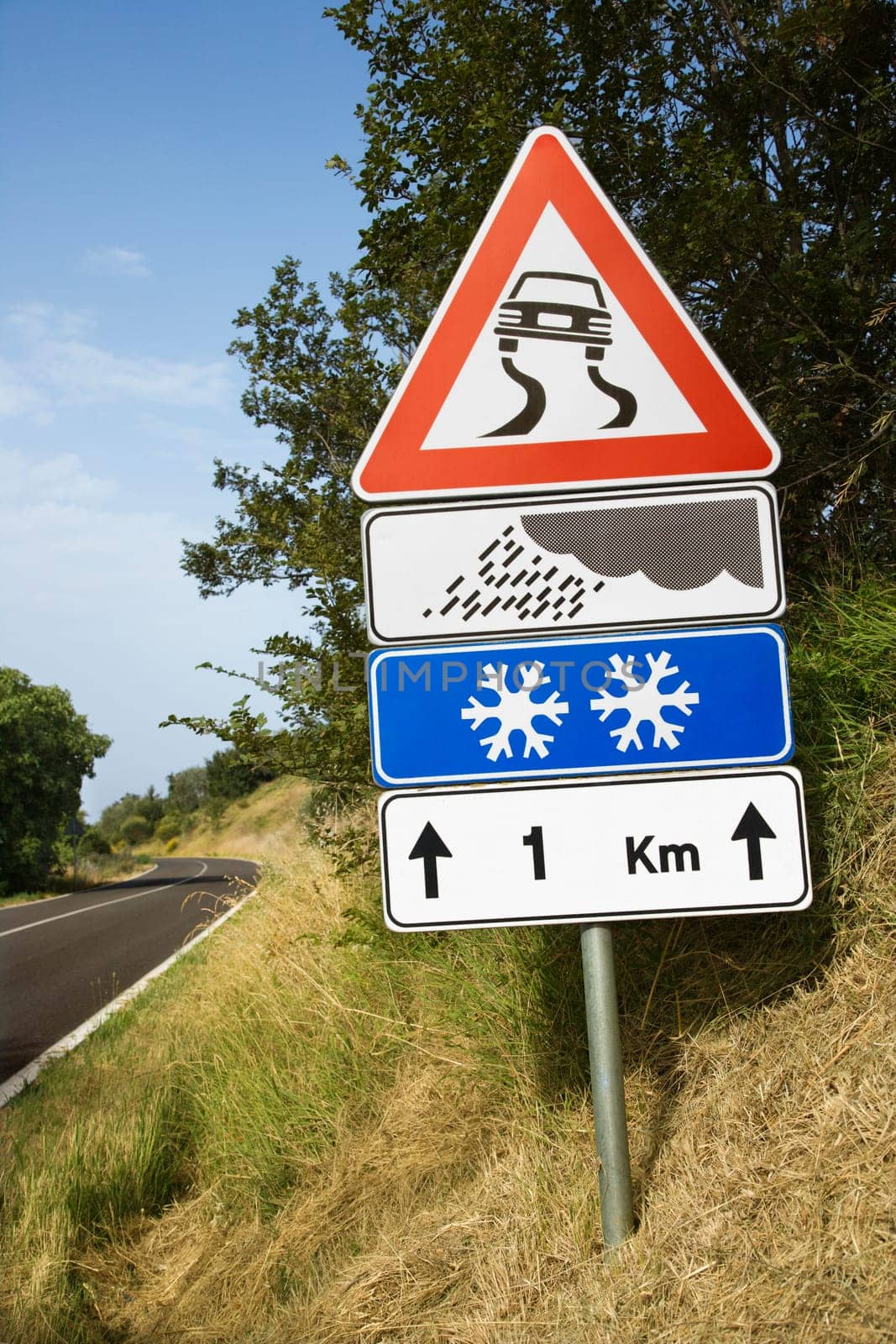 Signs warning of treacherous driving conditions on the side of a rural road. Vertical shot.