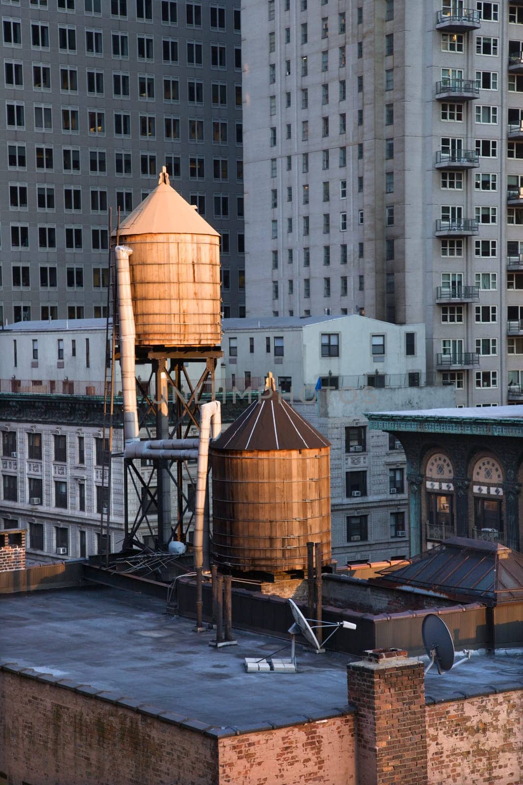 Cropped view of buildings in New York City and rooftop water towers. Vertical shot.