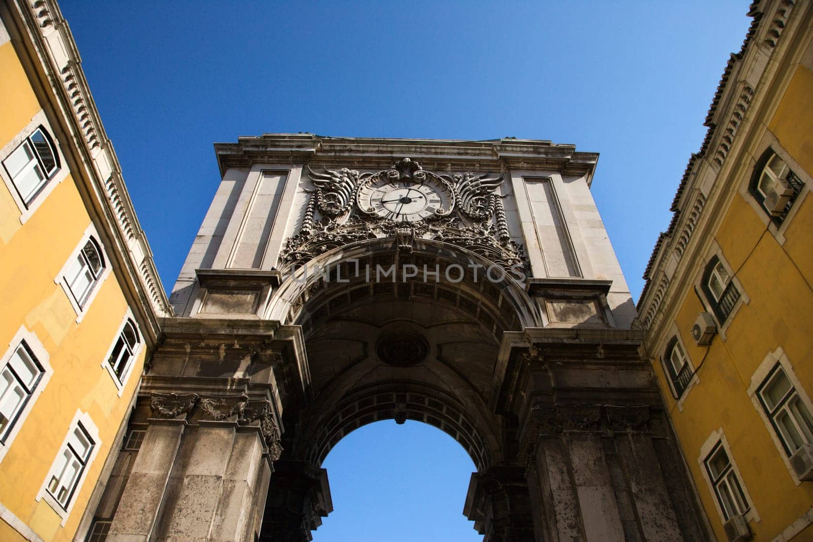 Arched tower with a clock spanning two buildings in Lisbon, Portugal. Horizontal shot.