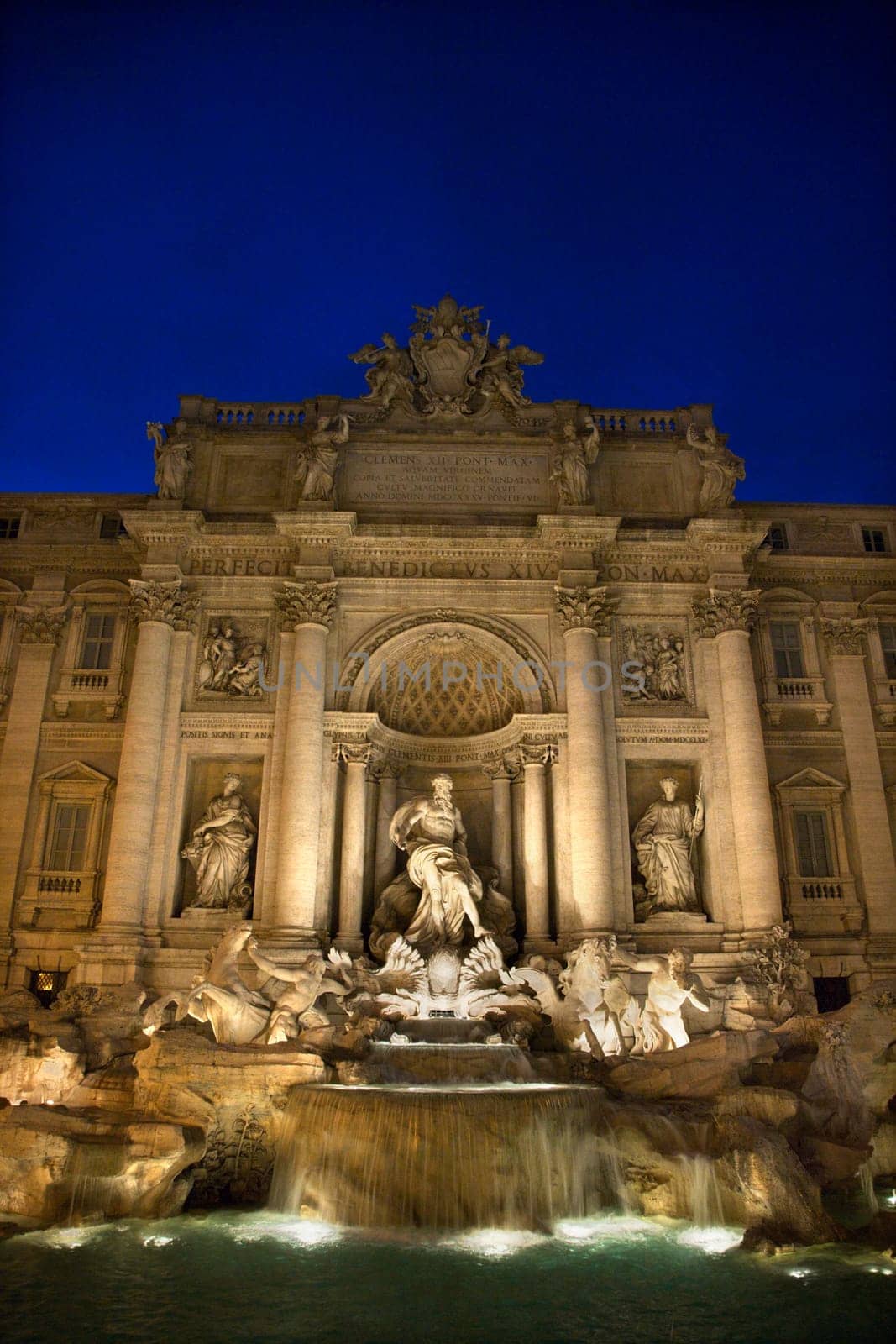 Trevi Fountain at night with lights under the water lighting the statuary. Vertical shot.