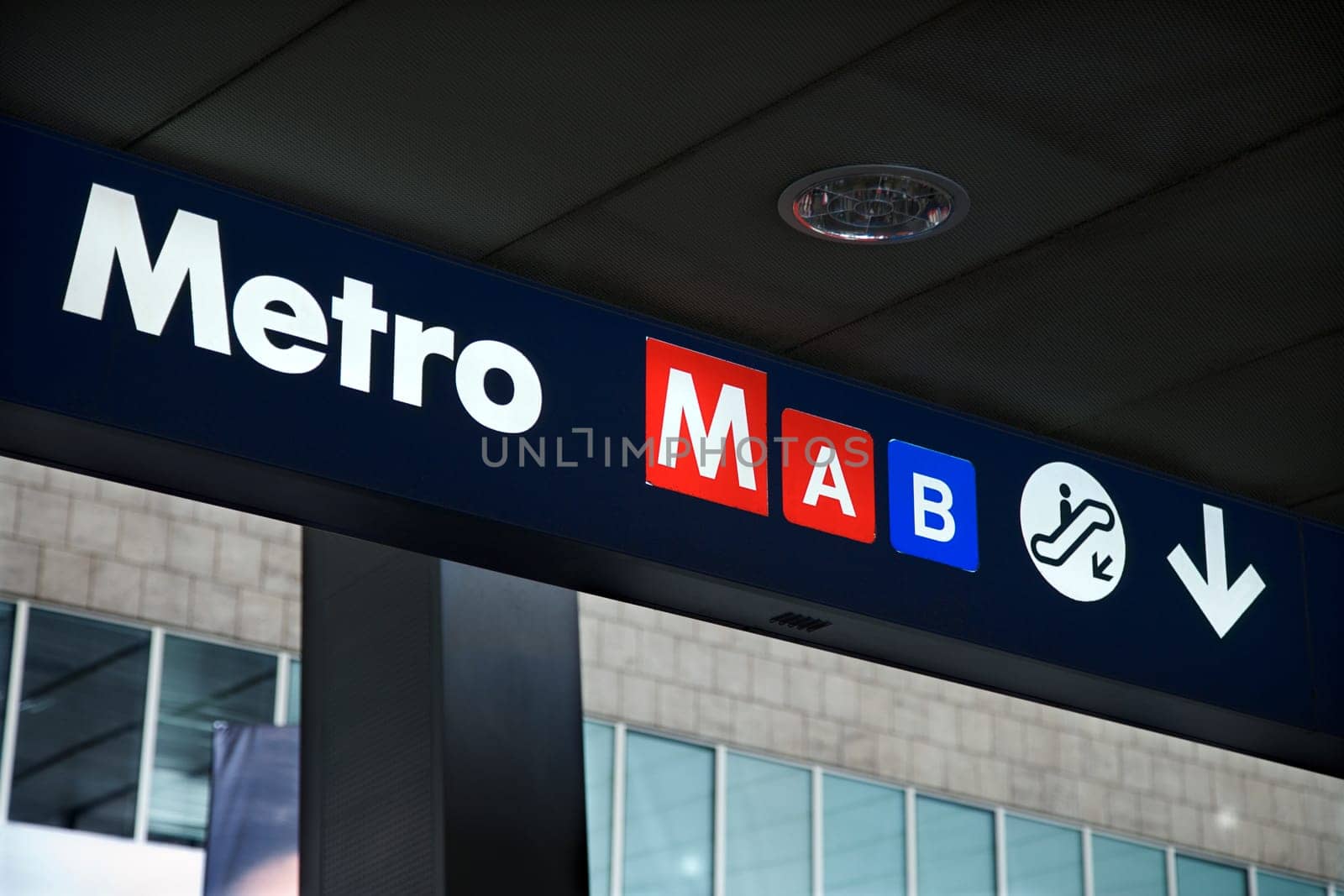 Metro sign indicating entrance via the escalator. Horizontal shot.