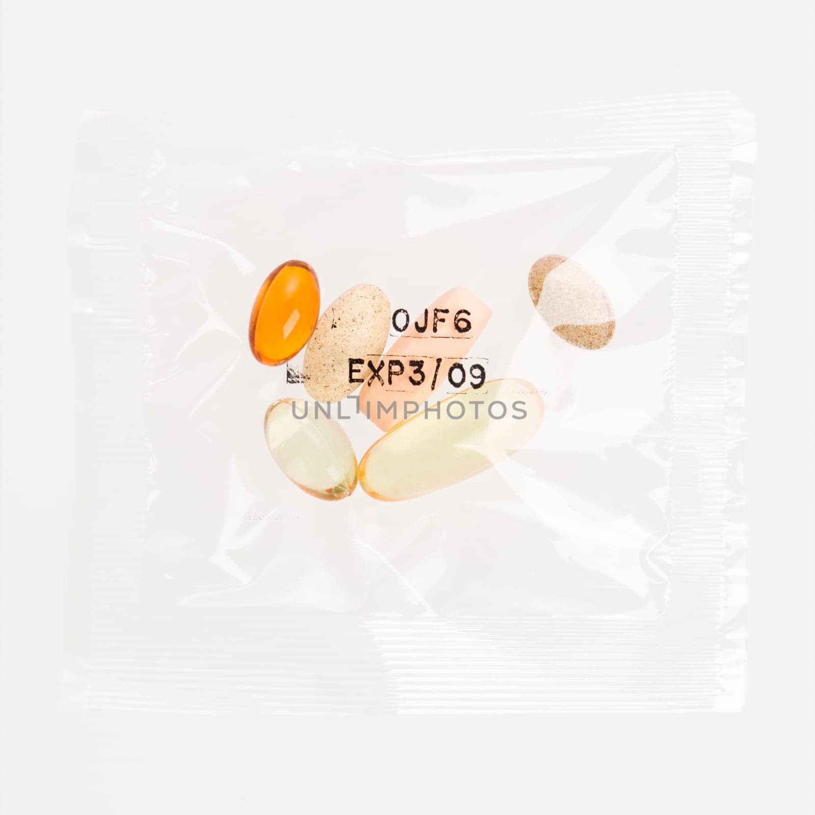 Pack of daily vitamin supplements in a clear plastic bag, stamped with an expiration date. Square format. Isolated on white.