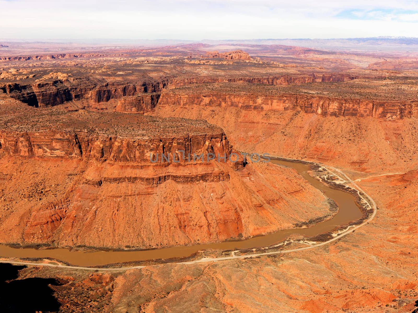 Aerial view of an arid, craggy landscape with a river running through it. Horizontal shot.