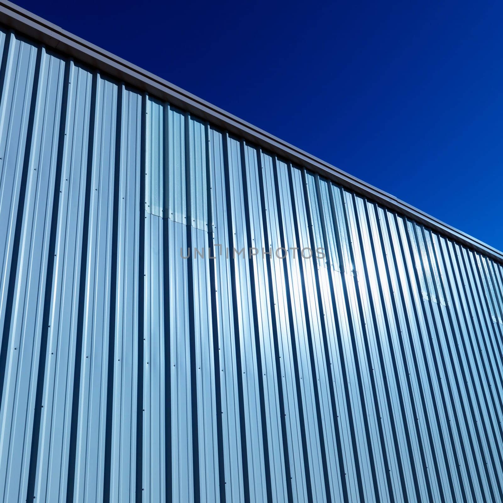 Cropped and low angle view of the side of a metal, industrial storage building. Square shot.