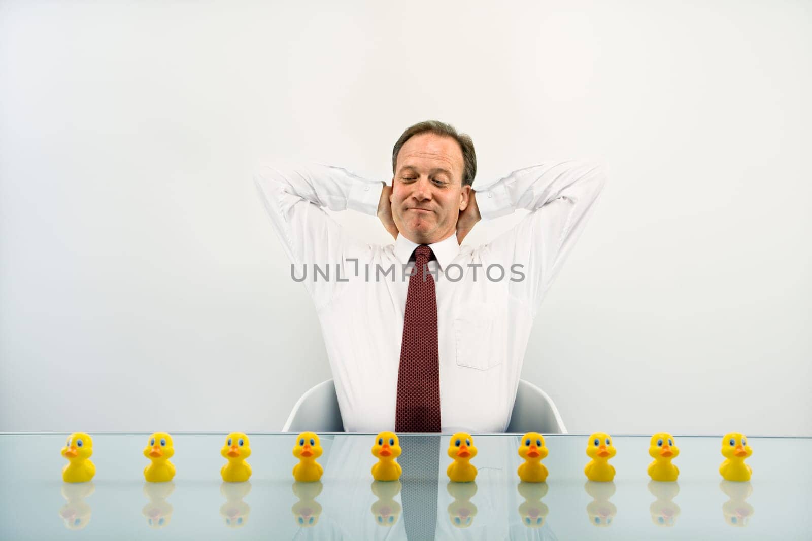 Portrait of middle aged  Caucasian businessman sitting at desk with ducks in a row.