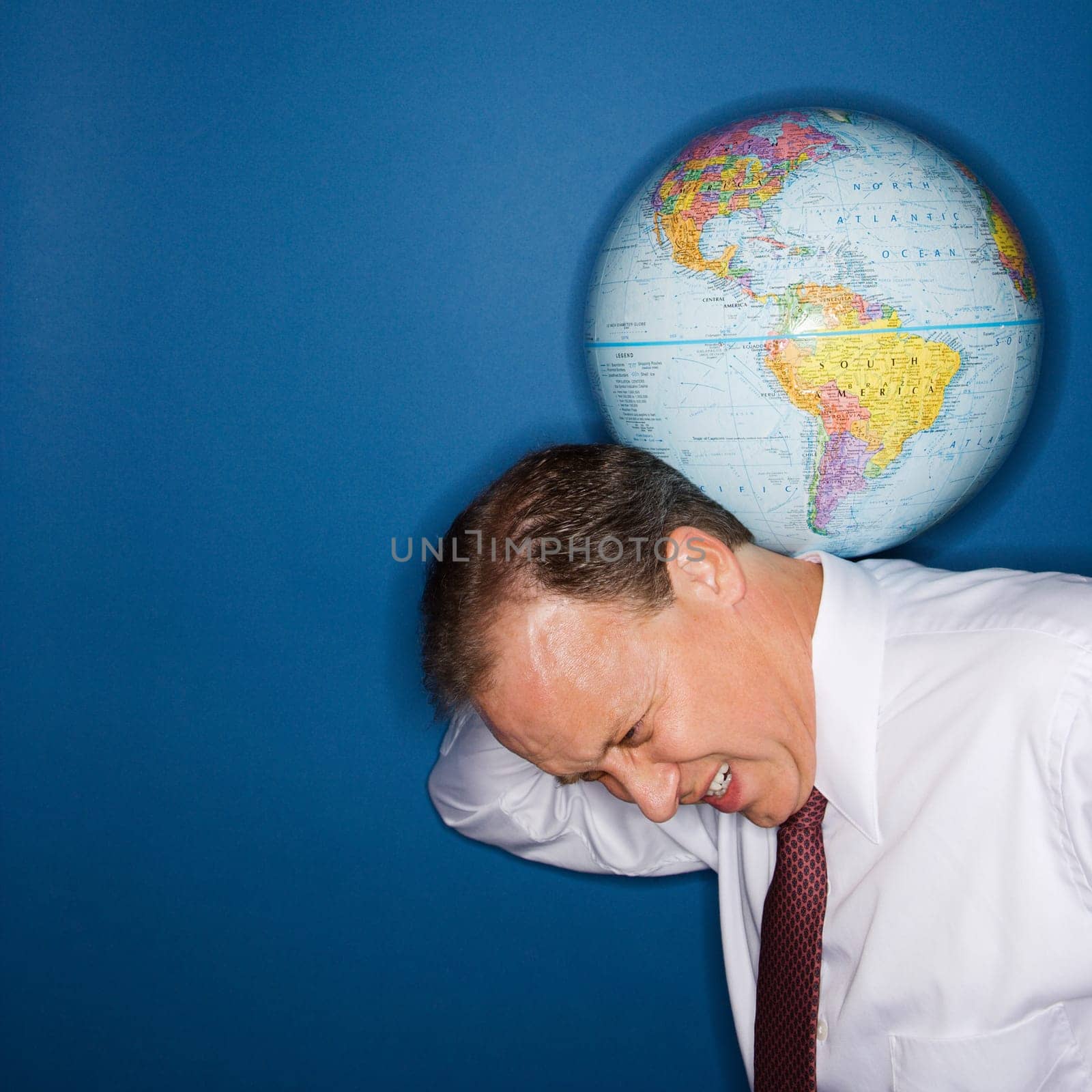 Caucasian middle aged businessman carrying world on shoulders straining.