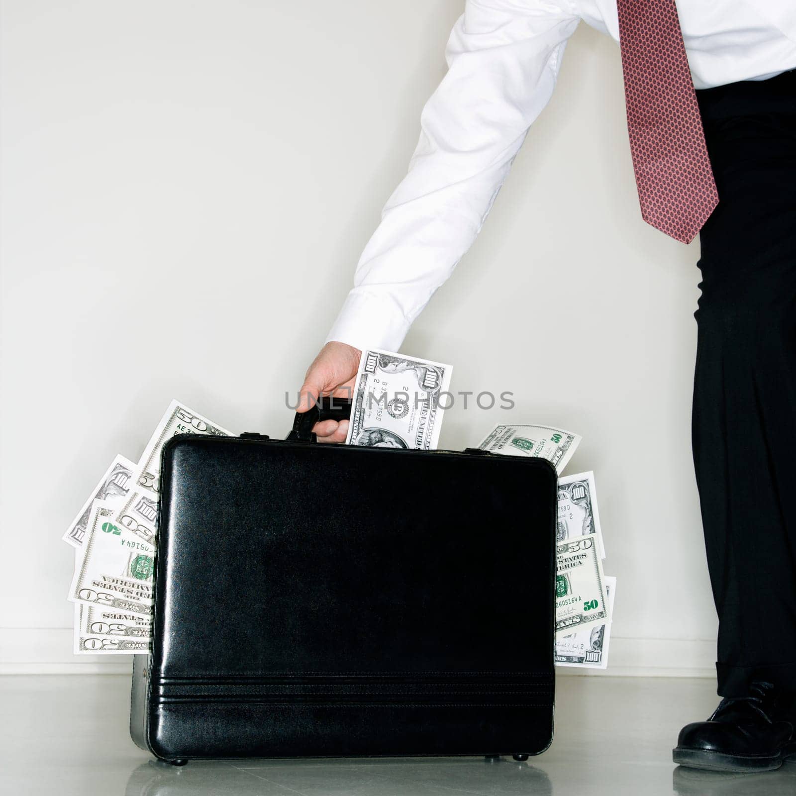 Caucasian middle aged businessman carrying briefcase overflowing with money.