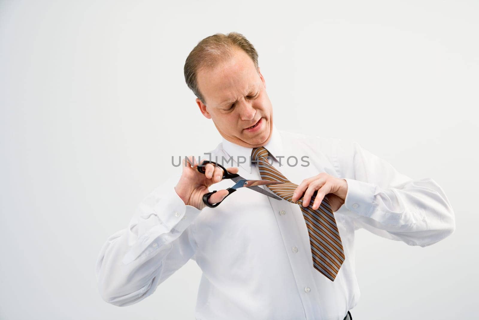 Caucasian middle aged businessman cutting off necktie with scissors.