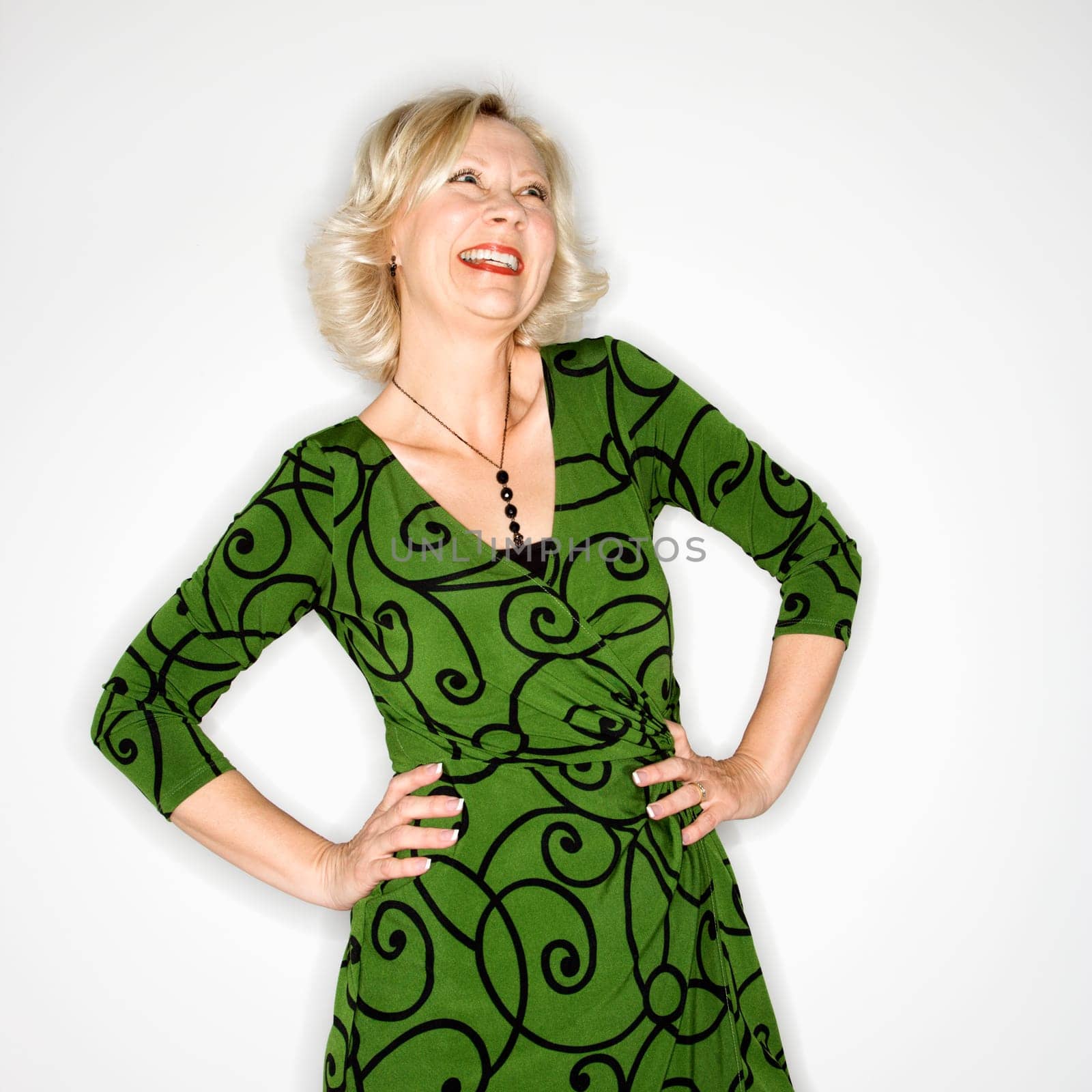 Portrait of Caucasian middle aged businesswoman standing with hands on hips laughing.