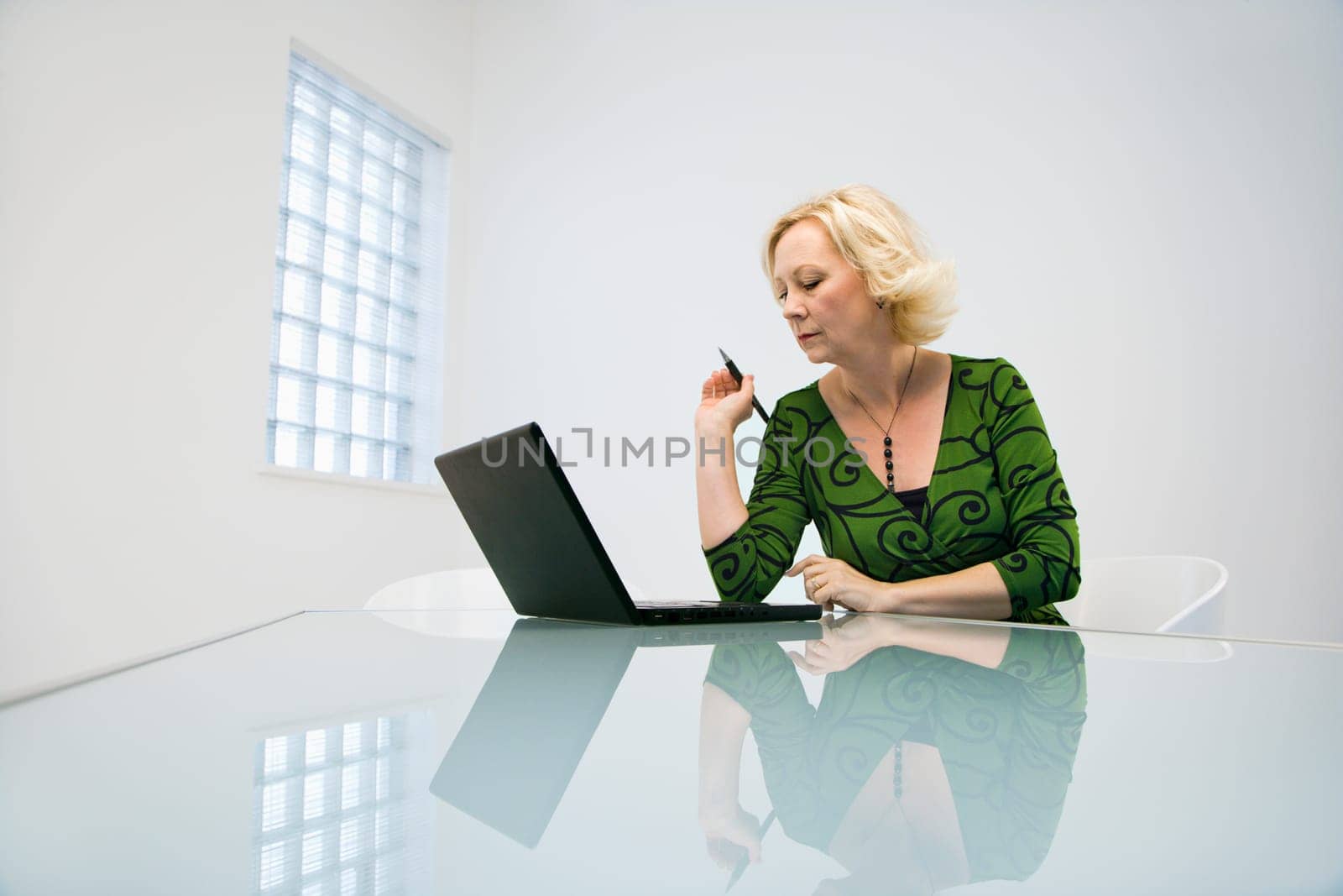 Caucasian middle aged businesswoman in office working on laptop computer.